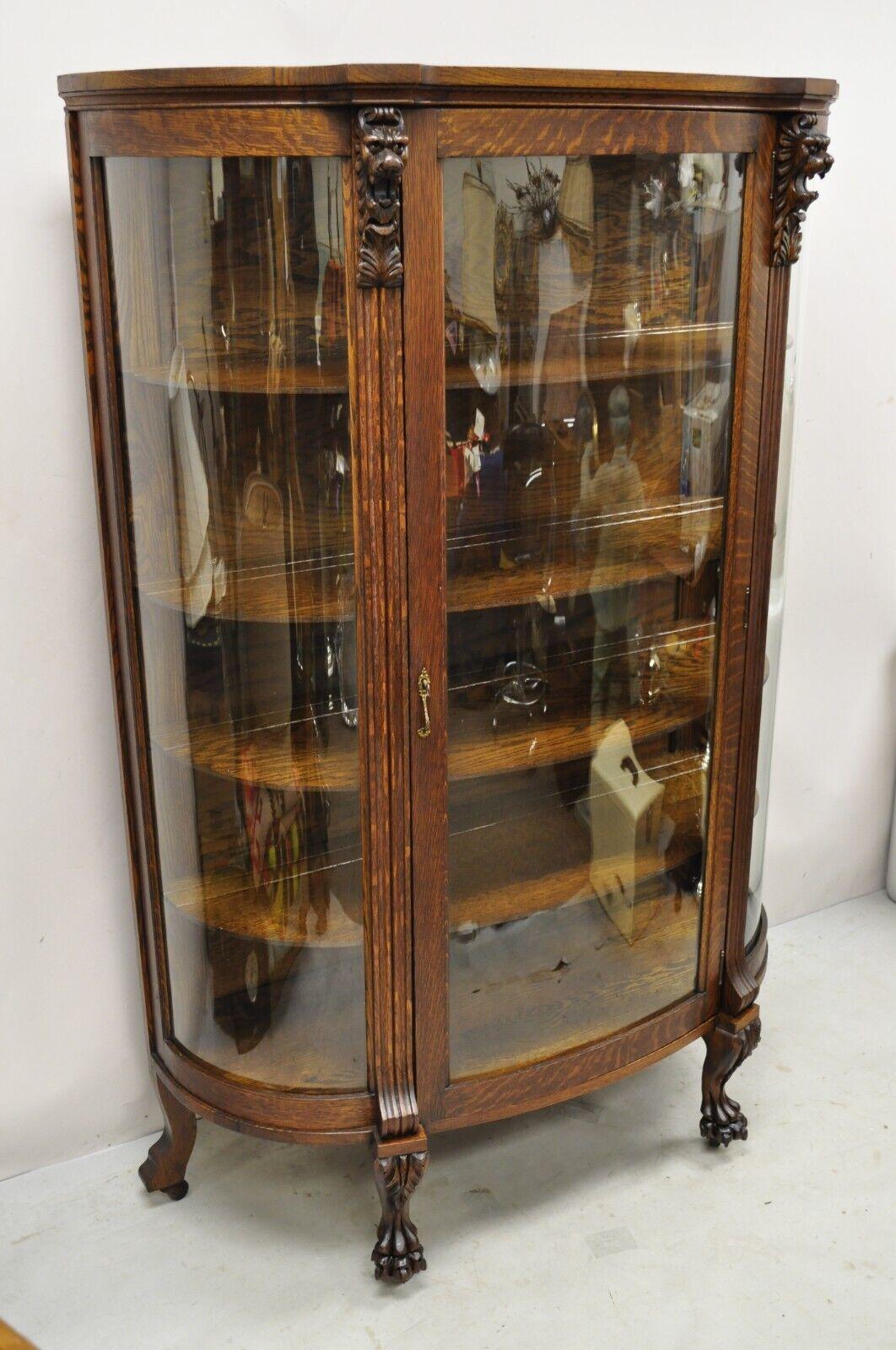 Antique American Empire Oak Carved Lion Head Paw Feet Bowed Glass China Cabinet. Item features a carved figured lion heads, carved paw feet, 3 panes of bowed glass, beautiful wood grain, working lock and key, 4 wooden shelves, very nice antique