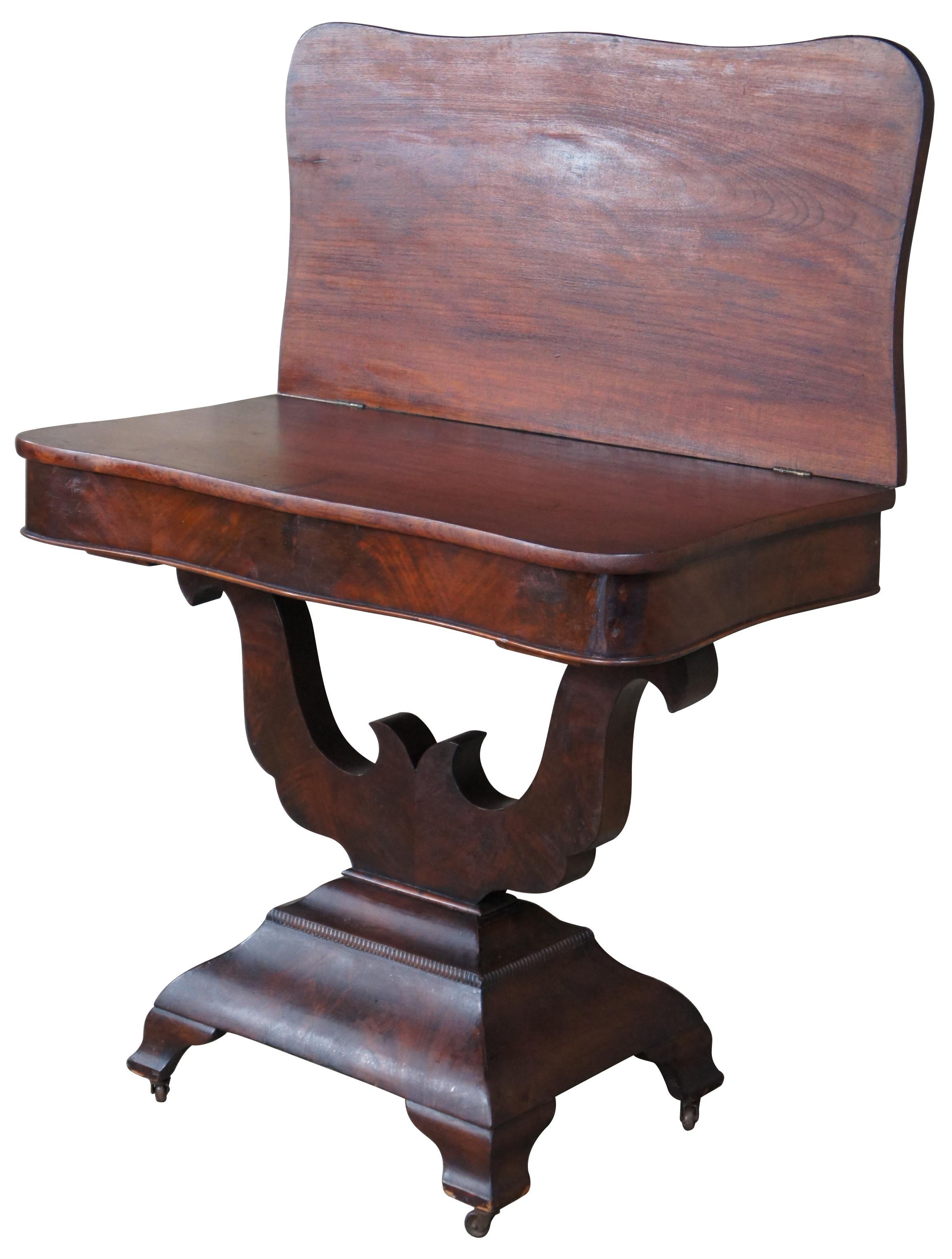 Antique 19th century, mahogany bookmatch veneered game table featuring rectangular serpentine form with a flip top game surface supported by lyre-form base.
 