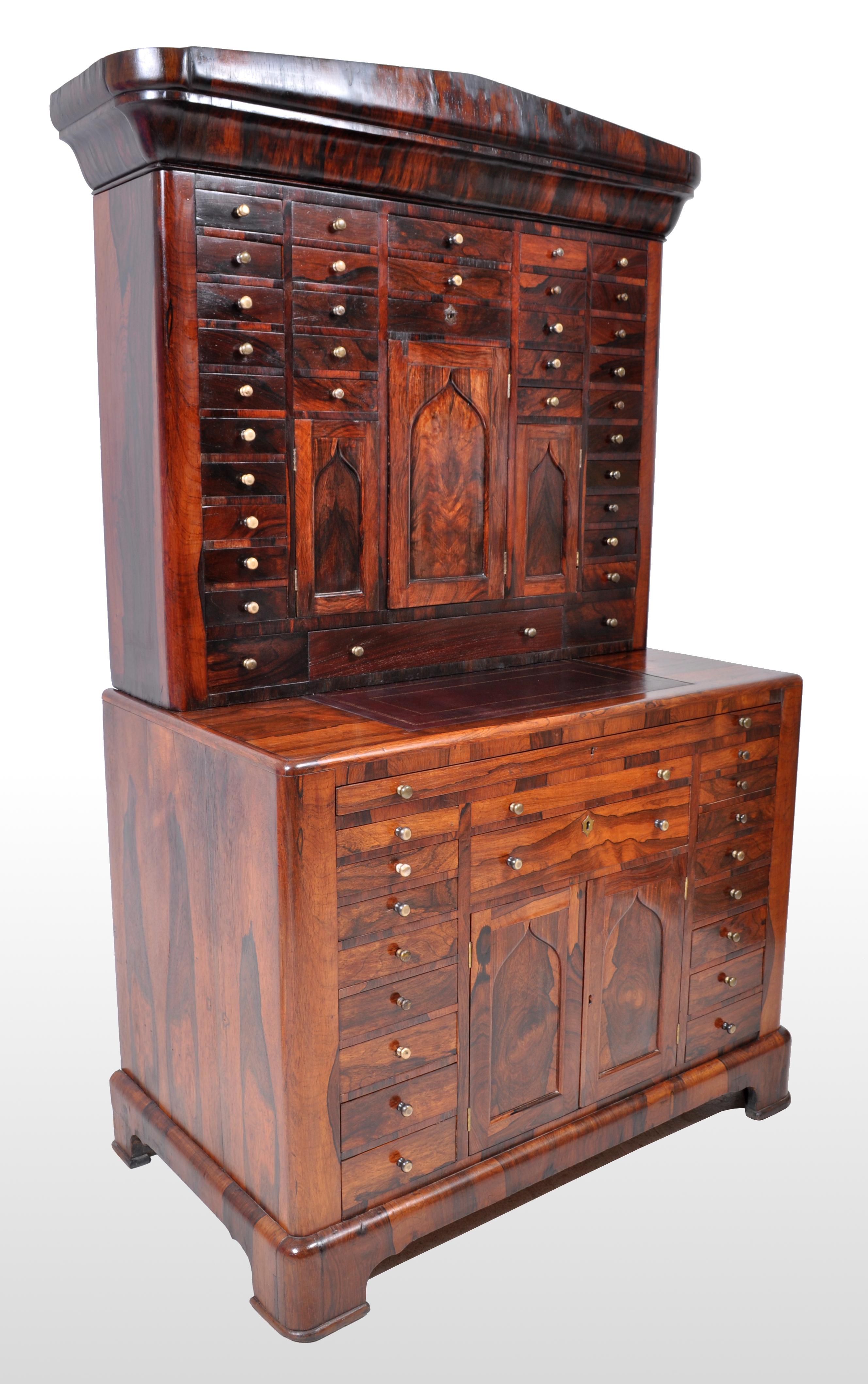 Antique American Empire rosewood dental / medical cabinet, circa 1820. This incredibly rare cabinet, in two section, made of figured rosewood throughout and having a neoclassical pediment to the top. Below the pediment is a cabinet with 34 drawers