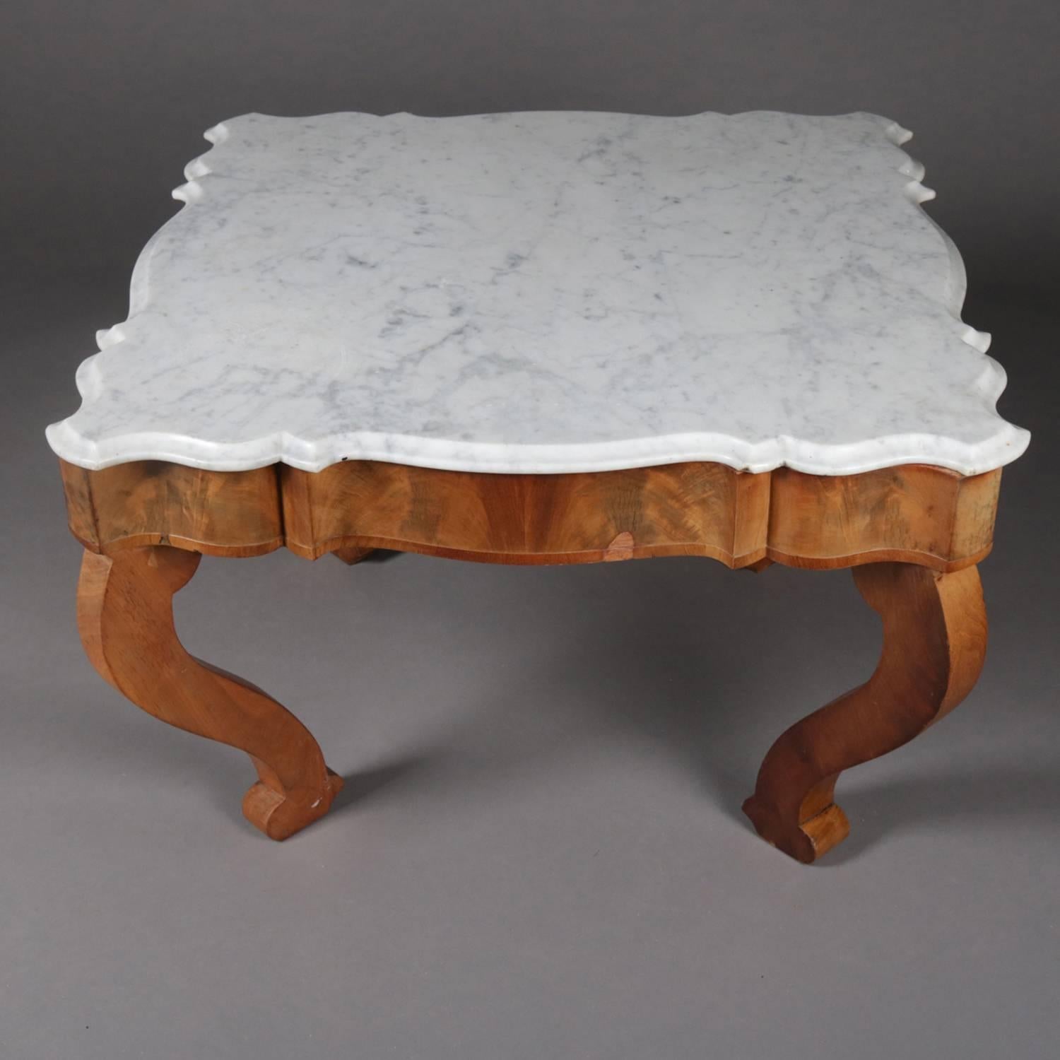 Antique American Empire coffee table features scalloped flame mahogany skirt supporting beveled marble top and raised on scroll for legs, c1860

Measures: 22