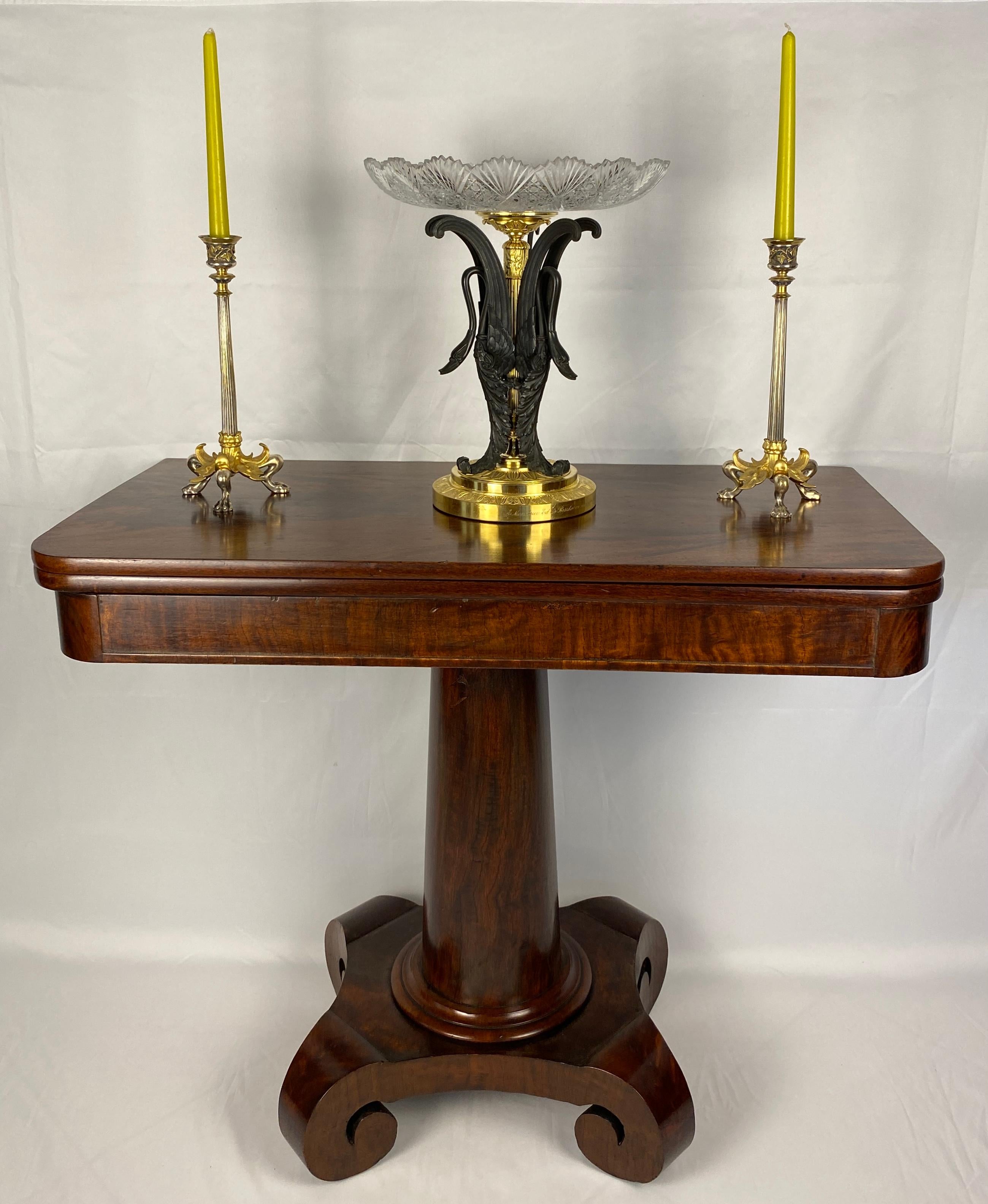 Elegant American Empire style game table, circa 1835. This versatile piece showcases classic design with a practical function. The swivel top, supported by a graceful cylinder column base, opens to reveal a spacious playing surface with hidden