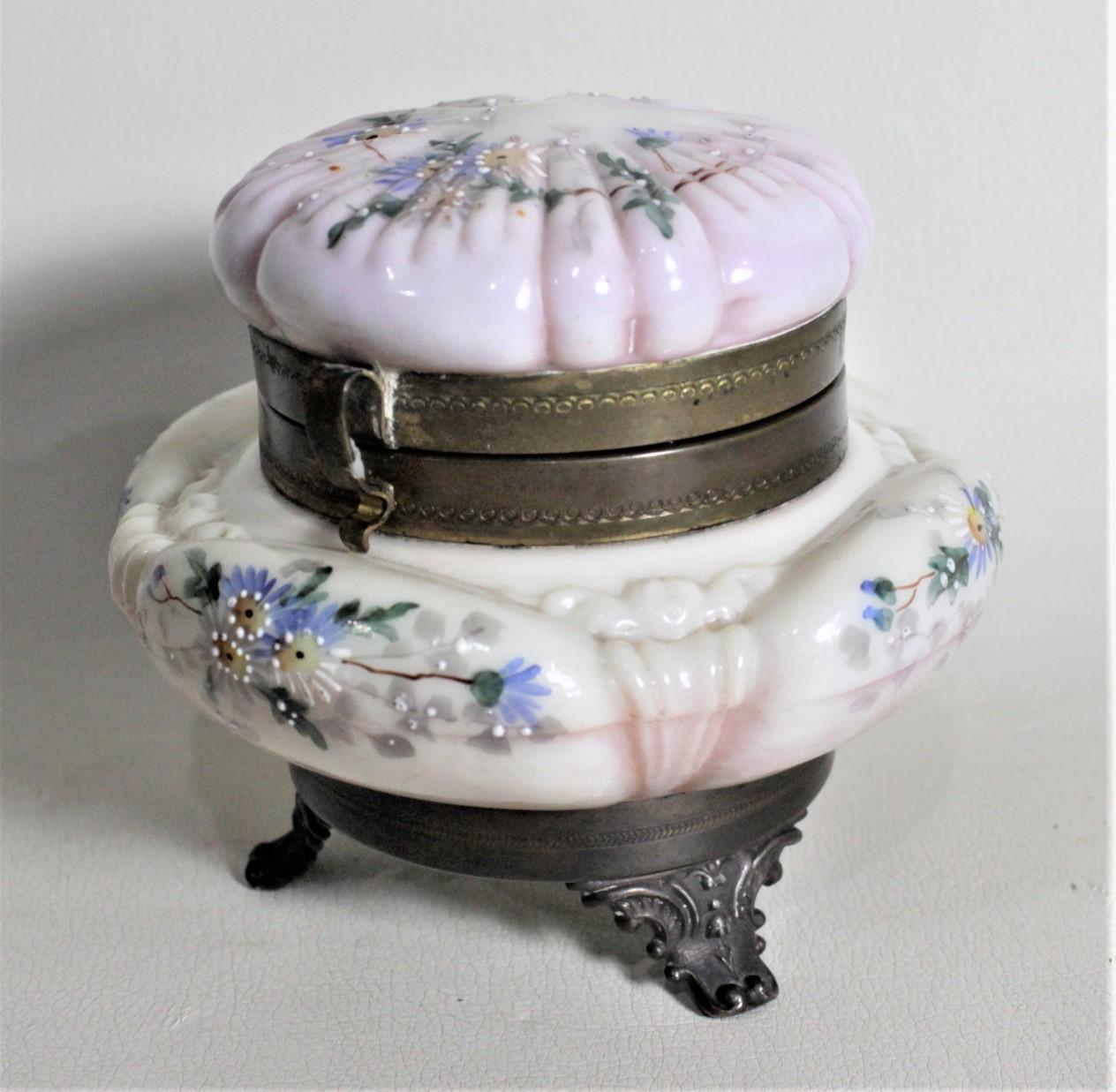 This antique pressed glass jewelry casket or jar is unsigned but presumed to have been made in the United States in circa 1880 in the period Victorian style. The jar is made of a cream base glass with a swirled rose colored glass that accents both