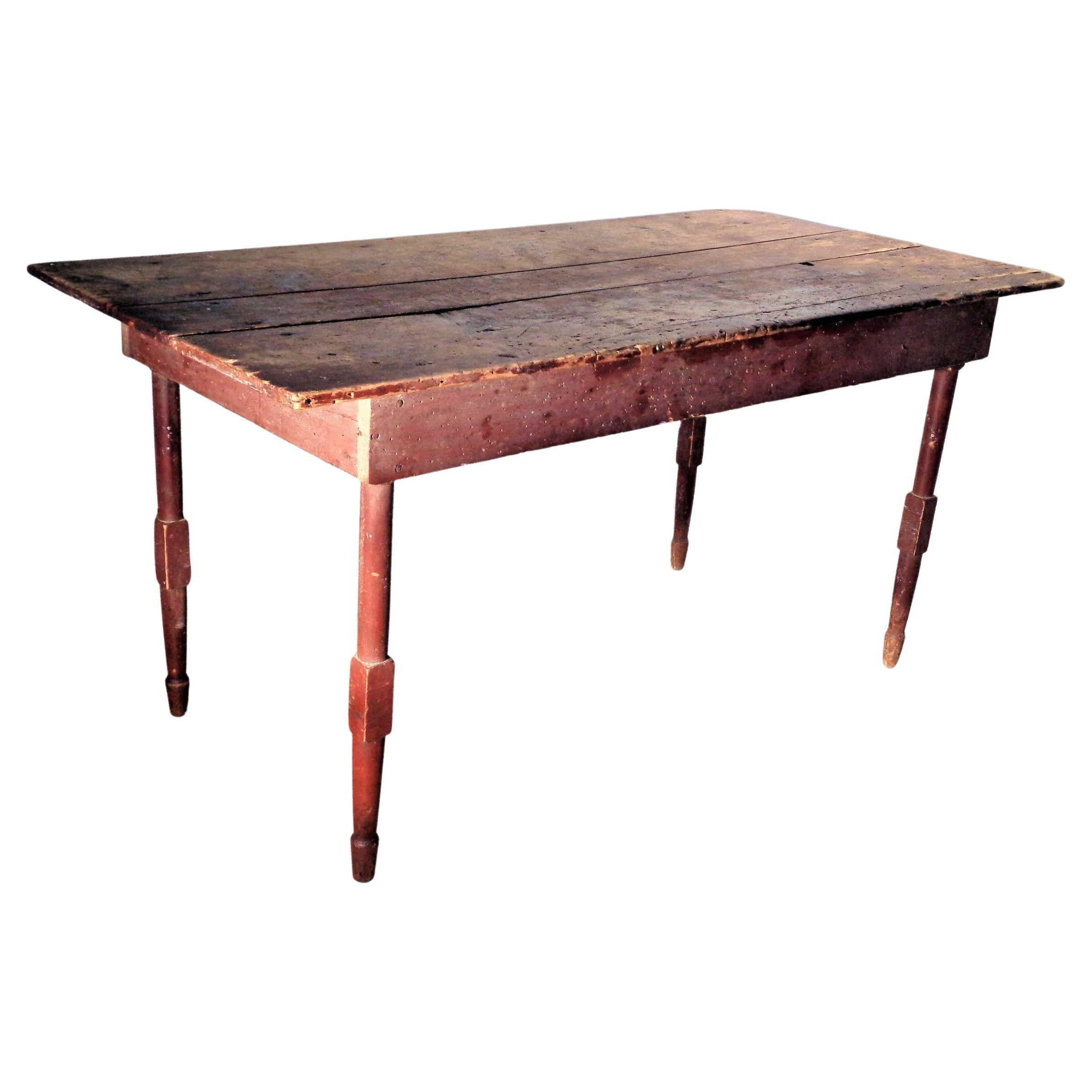 Antique American country farm table with unusually refined turned legs. Overall beautifully aged original surface color to red washed framework and the wide three board over hanging top. Perfect dining height with ample leg room - 24 inch height