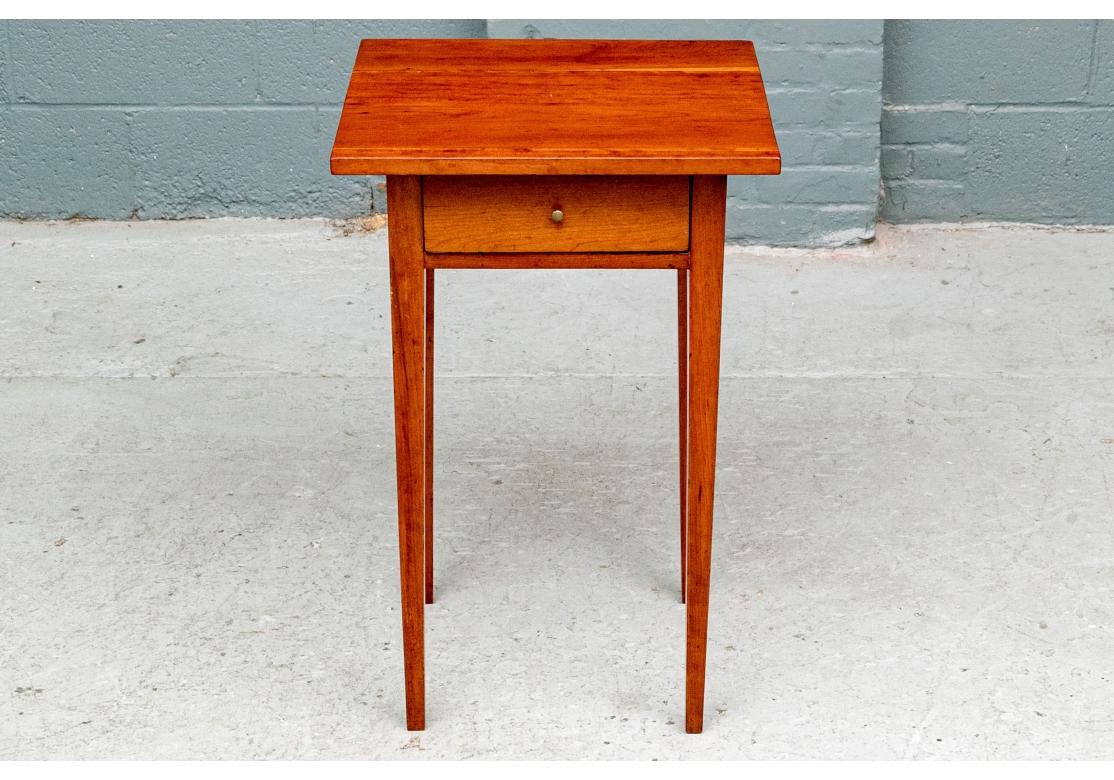 A classic American Federal stand here in cherry. With an overhanging square plank constructed top over a single frieze drawer with a small metal knob pull. Raised on square tapering legs. 

Dimensions; 18