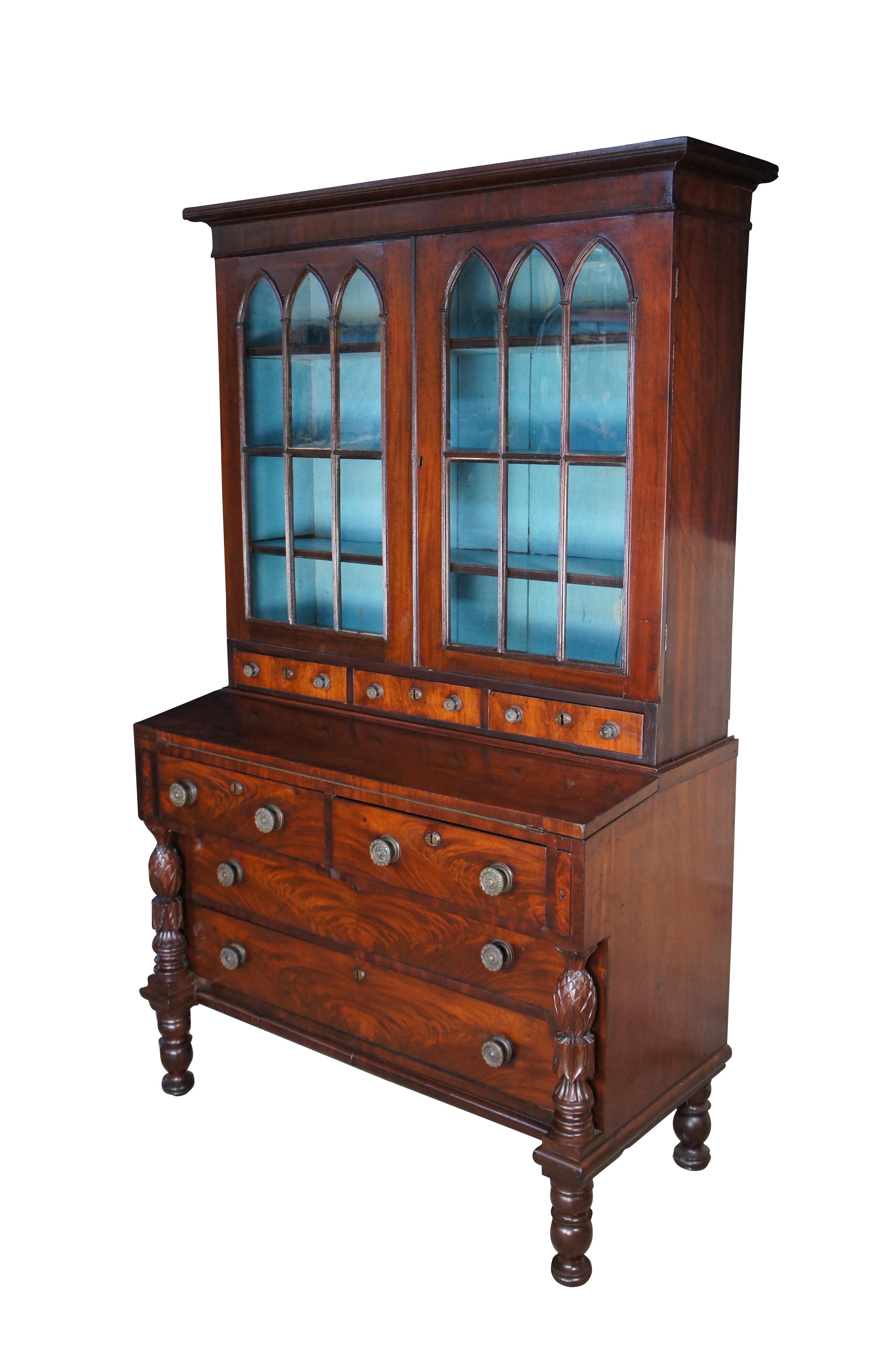 A fine and impressive antique early 19th century Federal Period flame Mahogany secretary and bookcase.  The bookcase features an eighteen pane Gothic arched cabinet front that opens to a beautiful blue painted interior with three shelves, and three