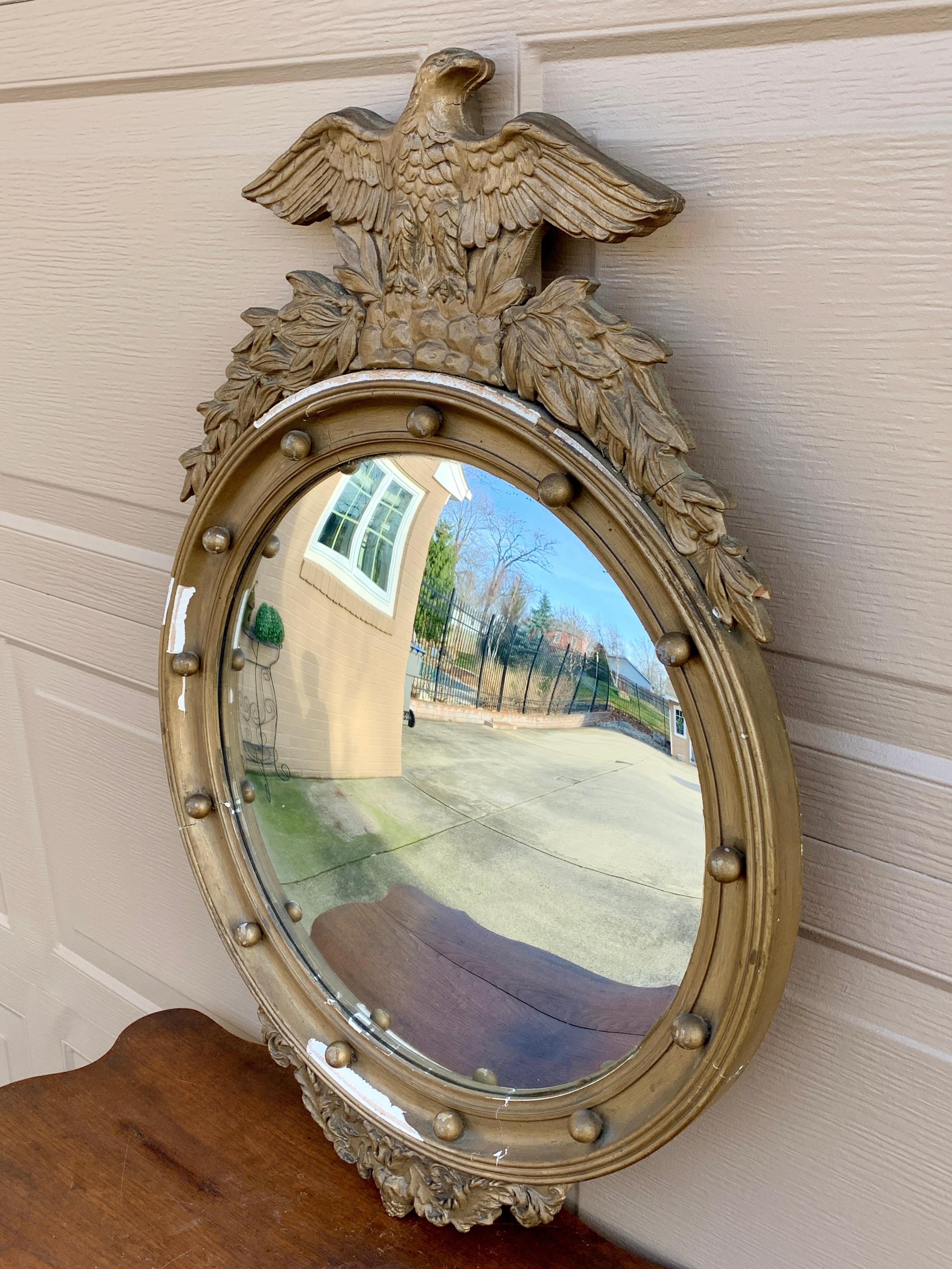 A gorgeous Federal or Regency style convex bullseye wall mirror featuring a carved eagle with open wings standing on olive branches and 13 small spheres representing the original 13 colonies around the inside perimeter.

USA, Mid 20th