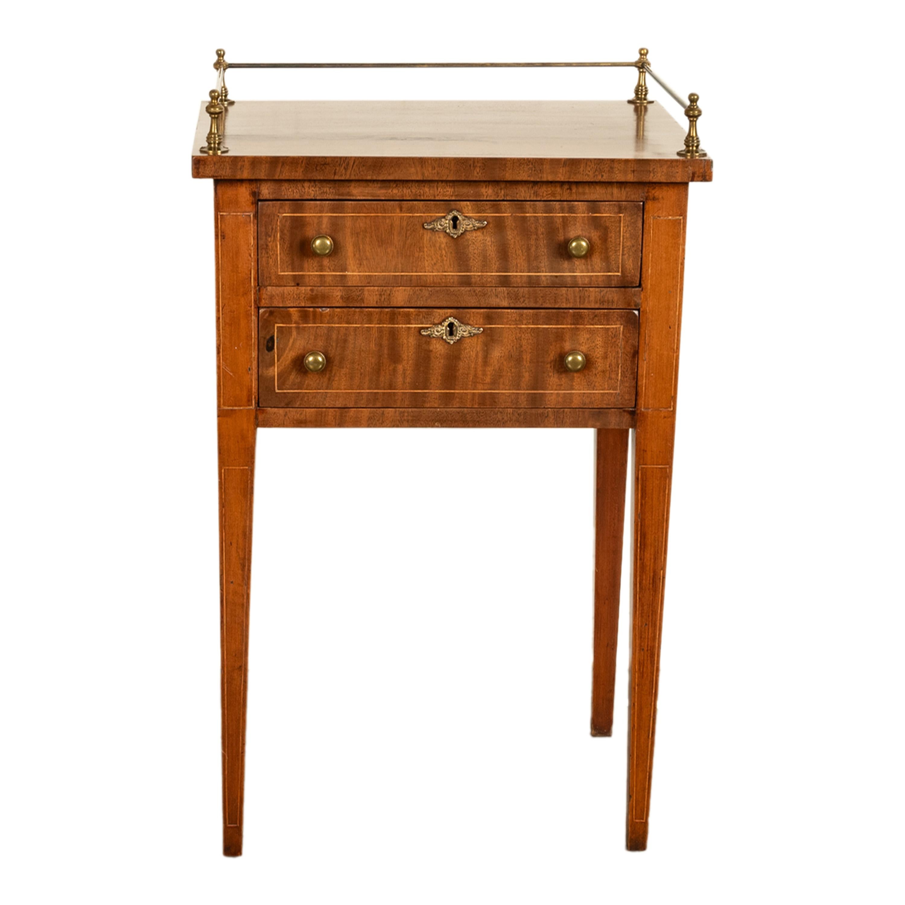 Una buena mesa auxiliar o de trabajo antigua de caoba con incrustaciones Federal Americana y galería de latón, hacia 1810.
La mesa tiene cuatro columnas torneadas de latón con remates de bola, unidas por raíles circulares de latón; está provista de