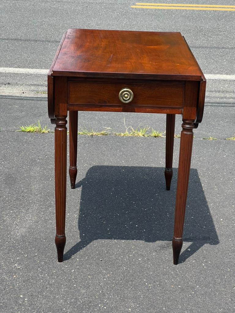 Adéntrate en un mundo de elegancia clásica americana con esta Antigua Mesa de Caoba de un Cajón de la Época Federal Americana, fabricada hacia 1830. Esta pieza es un excelente ejemplo del estilo Federal, que destaca por su simetría, sencillez y