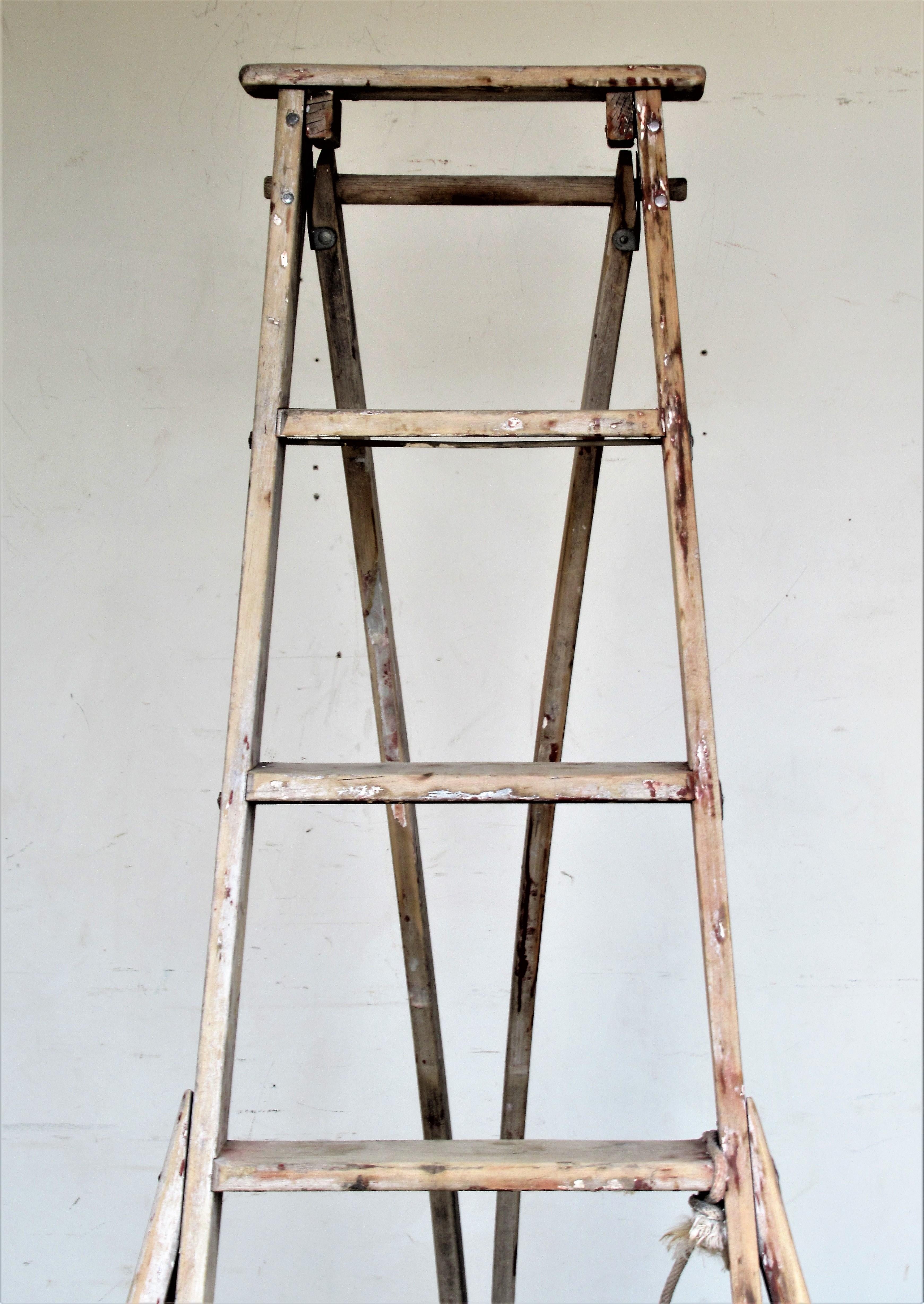 Vintage American wood and metal riveted folding orchard harvest fruit picking ladder in nicely aged old pale surface to wood with some scattered areas of old paint. When in upright extended position it measures almost 72