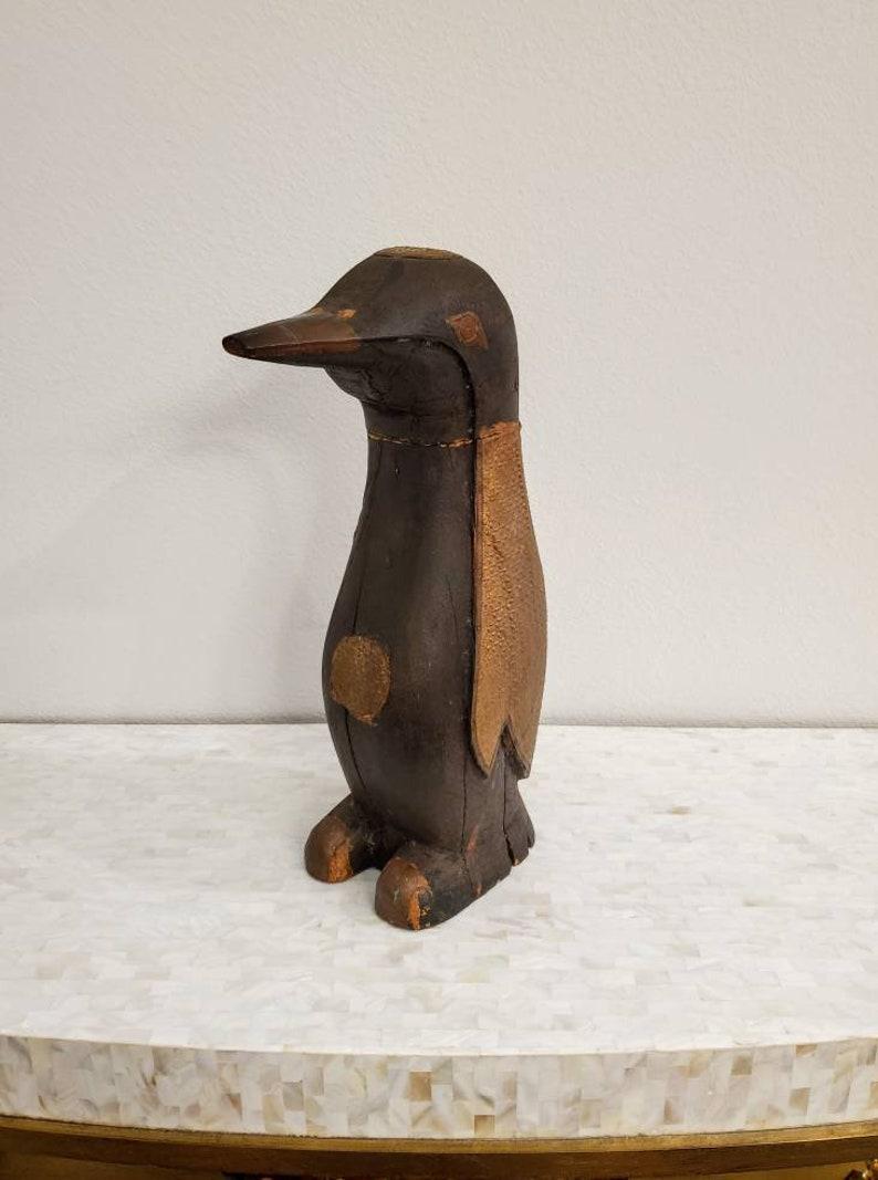 An early 20th century American hand carved and painted black wooden penguin sculpture. The primitive, freestanding figure is uniquely decorated, having textured and patinated embossed gilt metal accents, rustic yet elegantly sophisticated and