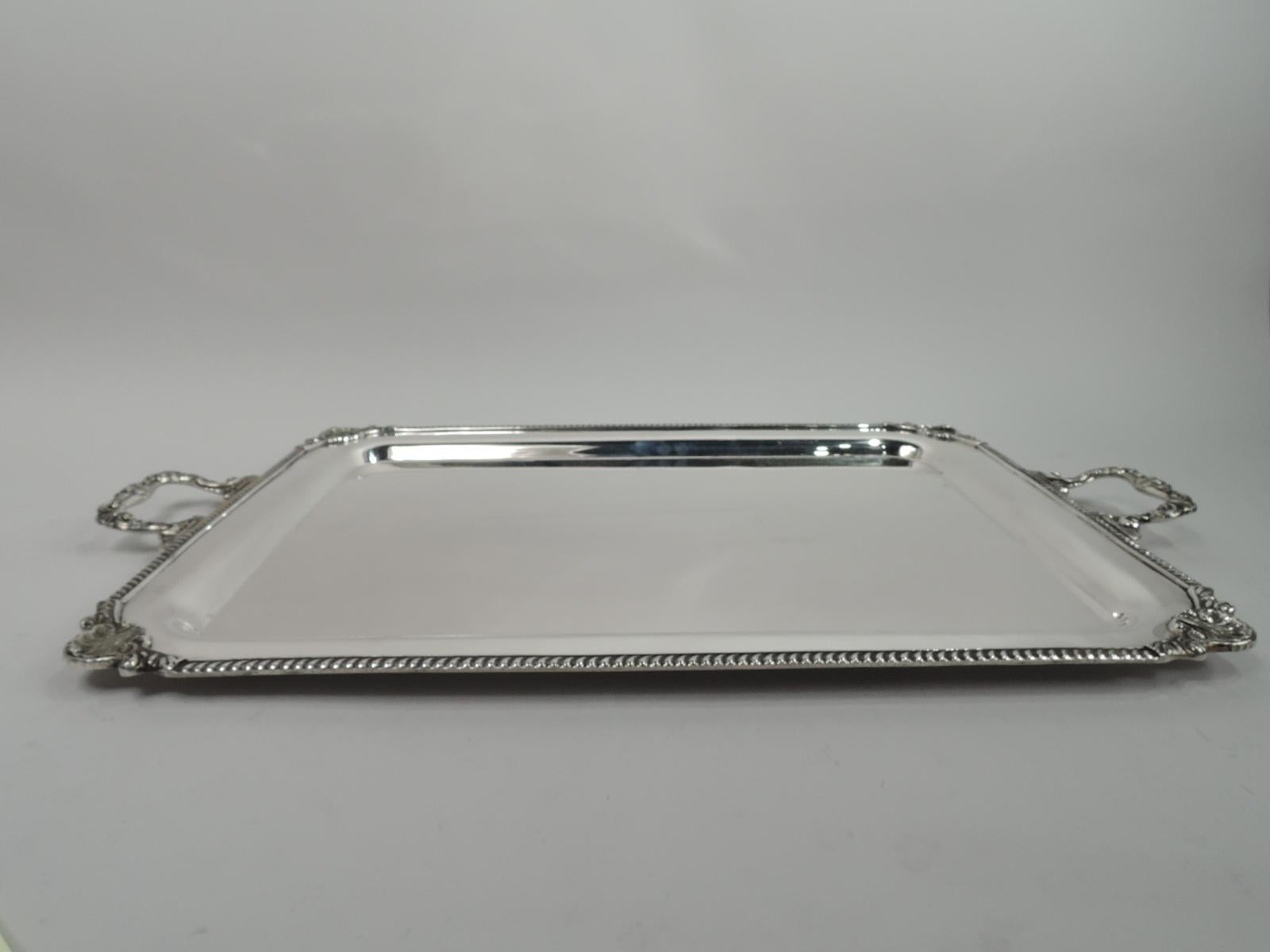 Georgian-style sterling silver tea tray. Rectangular with curved corners. Gadrooned rim with corner shells. Scroll, shell and leaf bracket end handles. Old fashioned with enough heft to support Grandma’s set. Fully marked with stamp for Durham, a