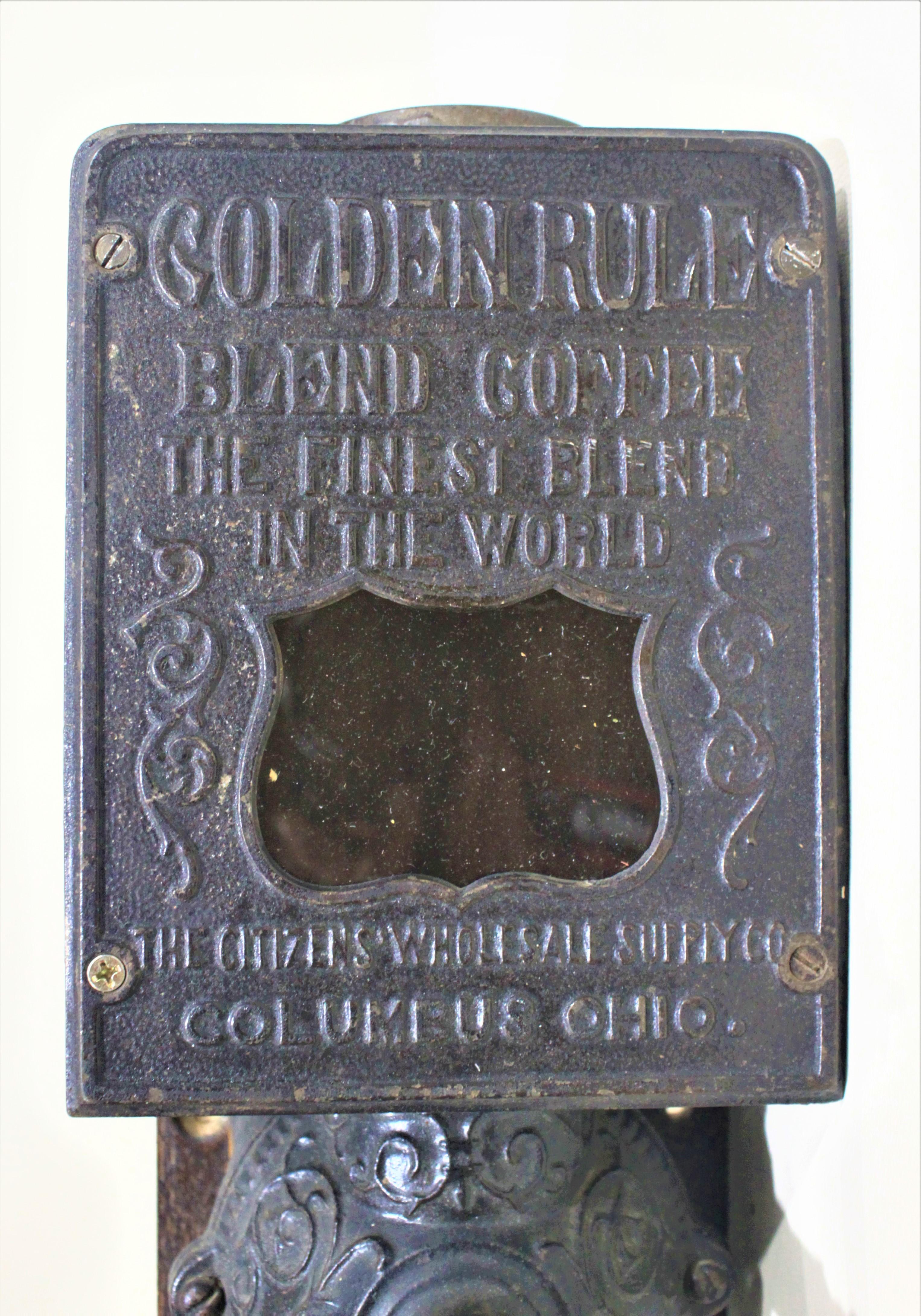 This antique cast iron and wooden wall mounted coffee grinder was made by the Arcade Manufacturing Company of Columbus Ohio and advertises 'Golden Rule' blended coffee. This coffee grinder is presumed to have been manufactured in the early 20th