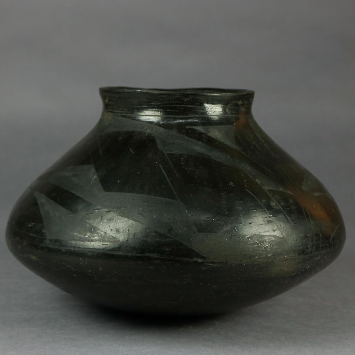 An antique American Indian San Ildefonso Pueblo pottery jar offers bulbous form with black on black geometric pattern, 20th century

Measures: 6.5