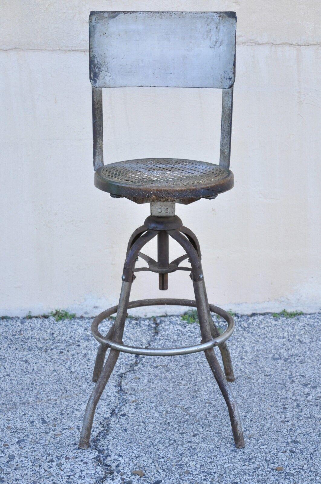 Antique American industrial metal drafting work stool with oak and cane seat. Item features a bentwood oak round cane seat, metal frame and backrest, distressed finish, very nice vintage item, quality American craftsmanship, great style and form.