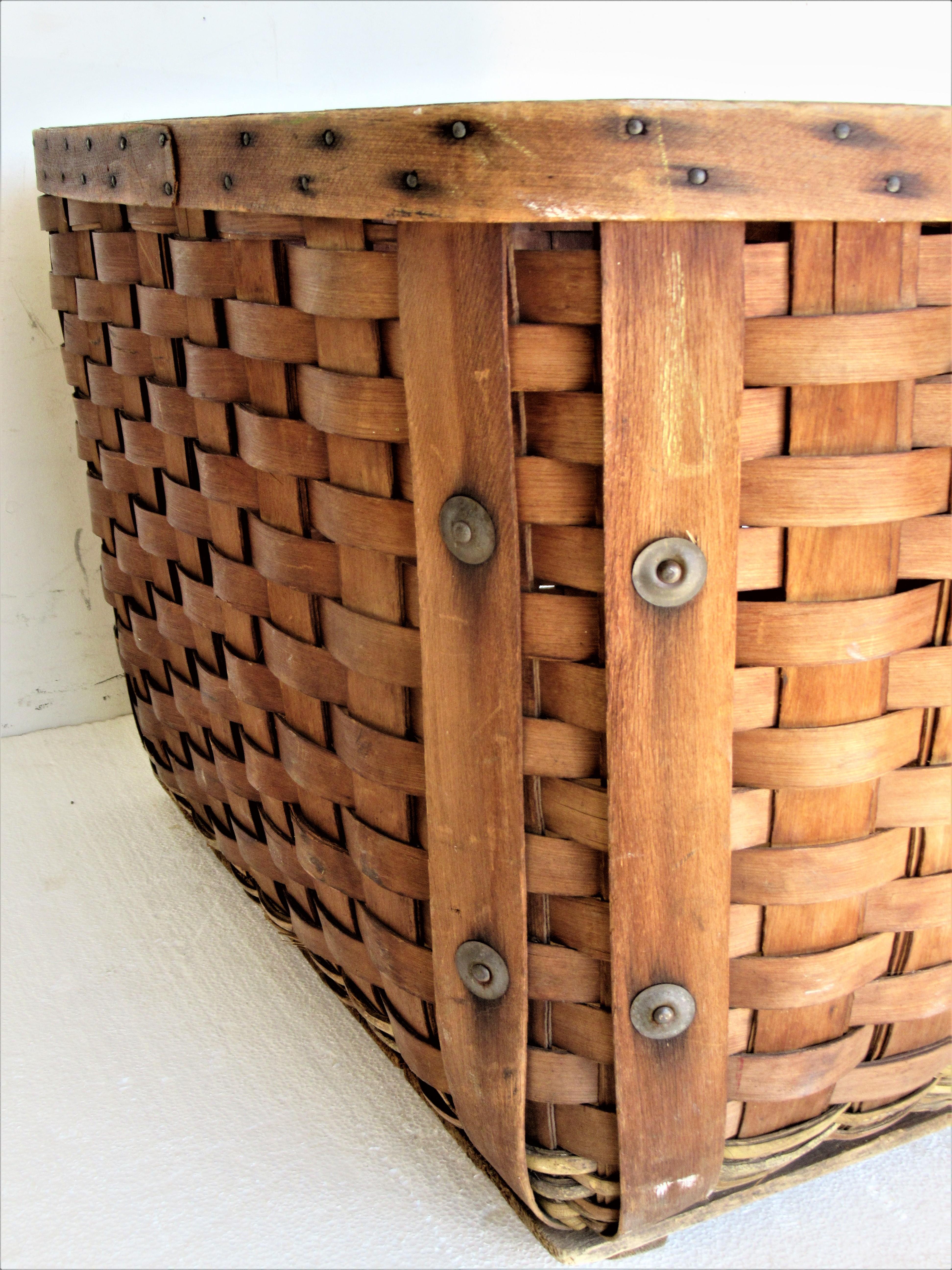 Antique hand crafted bent wood / splint and woven wicker large storage or gathering basket with two handles, tin metal buttons and wood planked bottom. A very good quality structurally solid fully functional decorative basket in overall beautifully