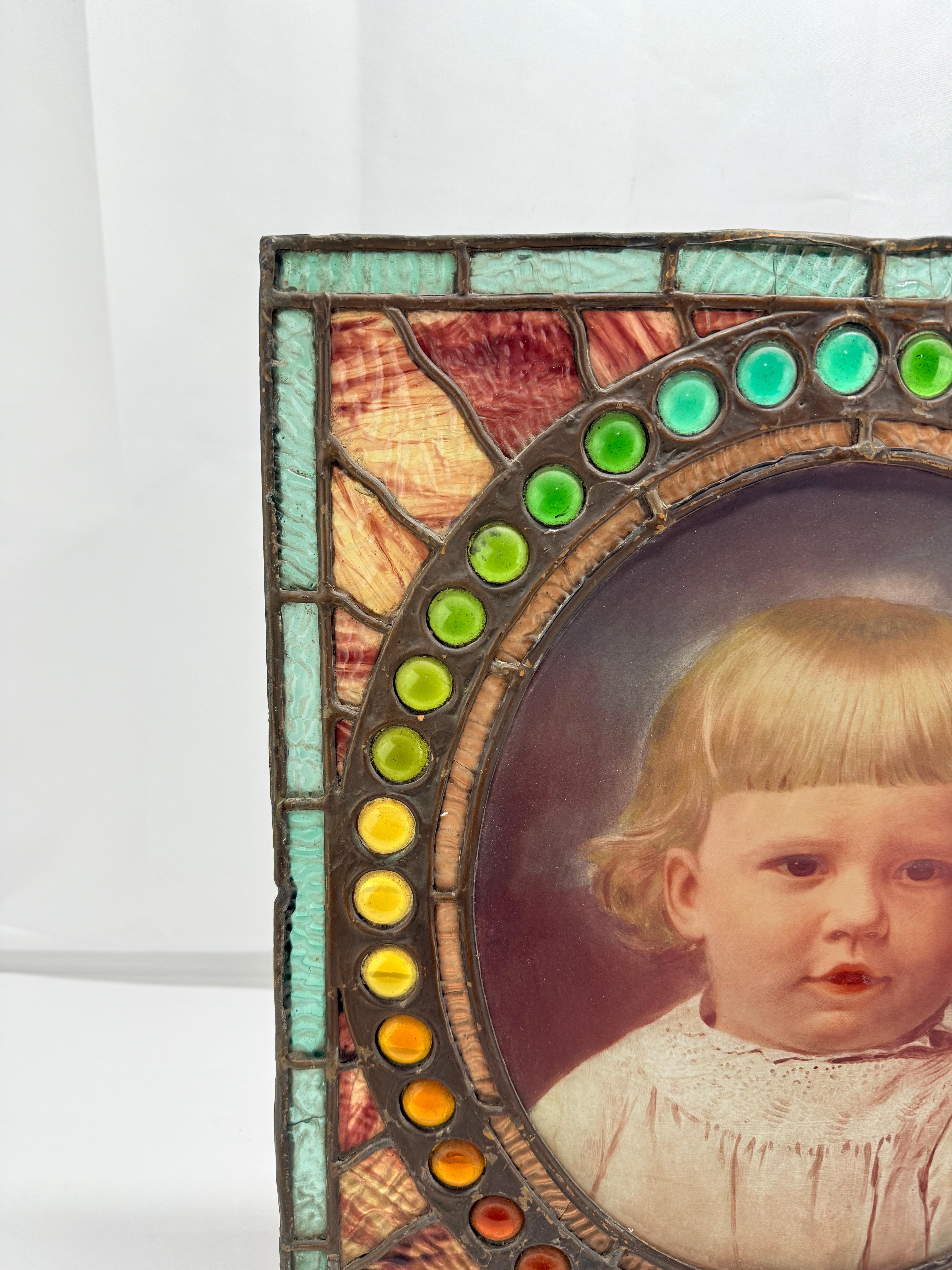 Retrato en vidrio invertido de un niño en vidriera y marco de vidrio enjoyado, estadounidense, hacia 1900-1910.

Este llamativo objeto aúna la delicada intimidad de la pintura sobre vidrio invertido con la luminosa materialidad de la vidriería y la