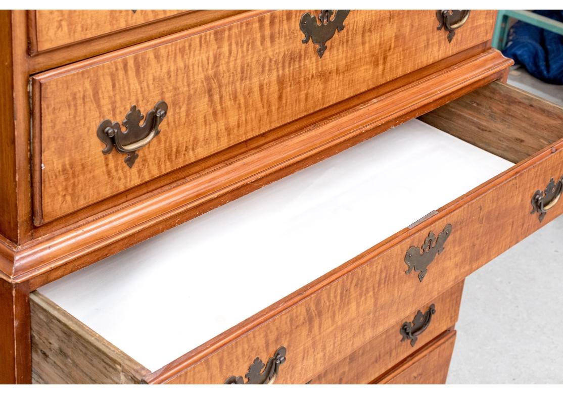 L'alta cassettiera è finemente realizzata in acero con cassetti in acero tigrato. La cassettiera superiore presenta una cornice a cavetto su due cassetti corti che fiancheggiano un cassetto corto centrale con un ventaglio finemente intagliato con un