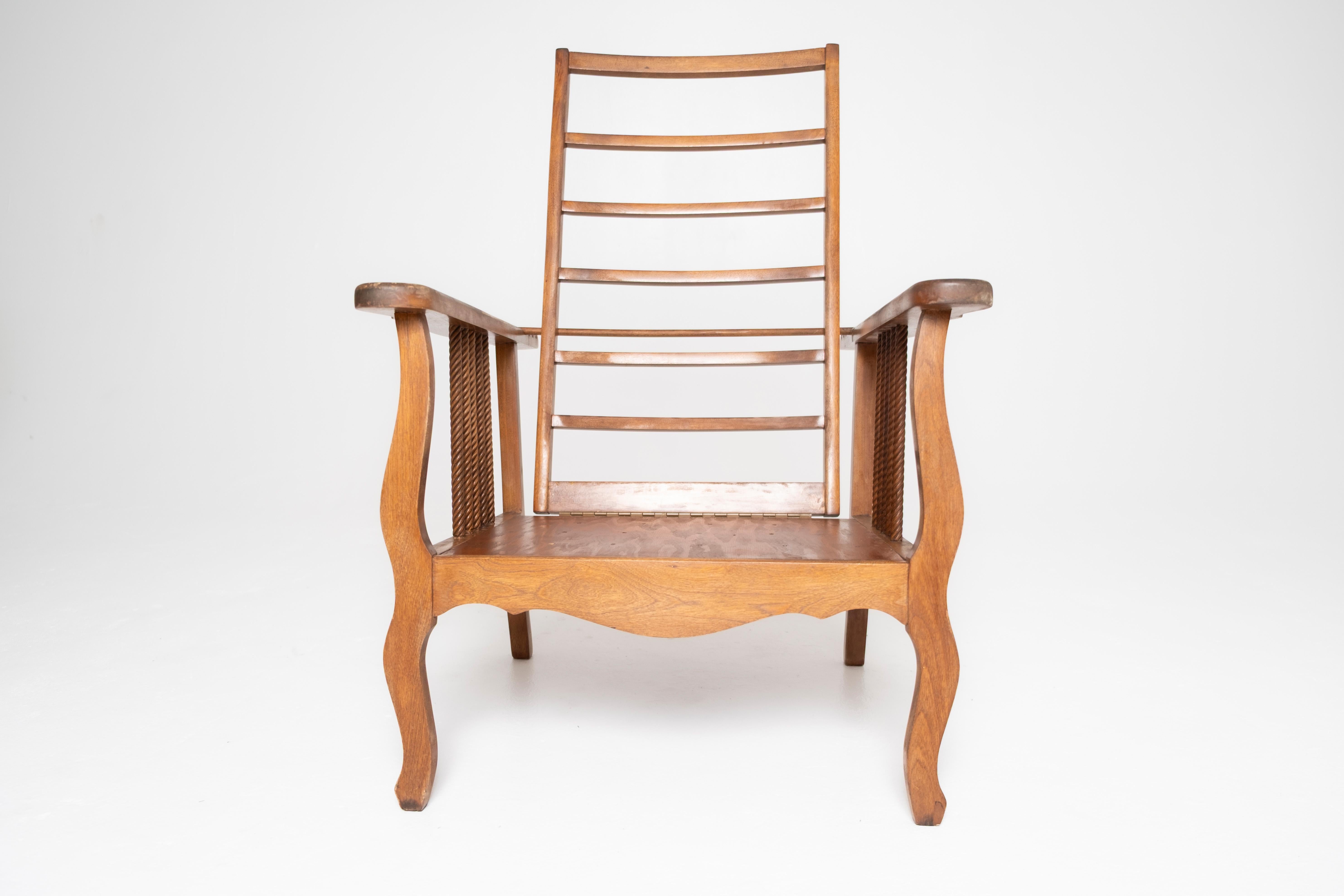 An Early 1900's American Morris chair frame, featuring a tall ladder-back design with adjustable reclining mechanism, sculpted arms, and turned rope-twist spindles along the sides. Rooted in the Arts & Crafts movement yet rendered with a rustic,