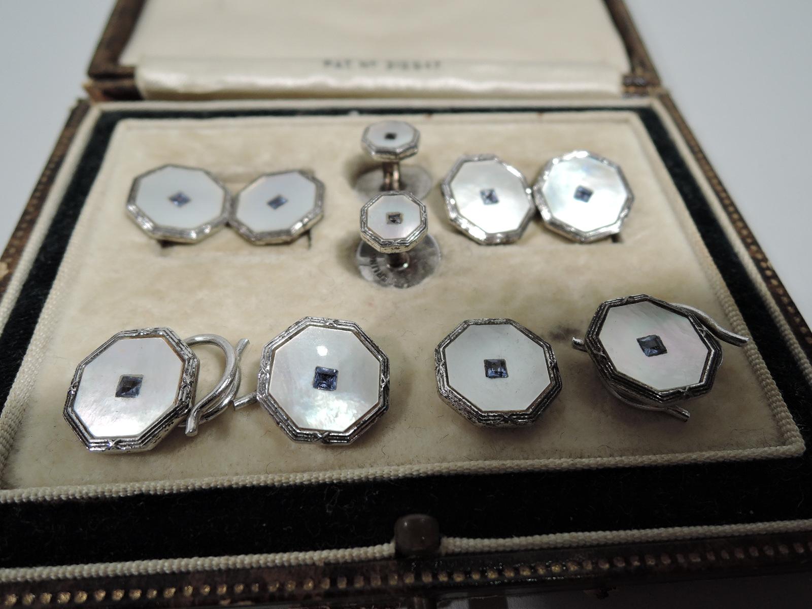 Handsome set comprising pair of cufflinks, pair of studs, and 4 buttons. Each: Octagonal mother of pearl centrally mounted with square sapphire; reeded sterling silver mount. United States, ca 1920s. Marked “Sterling” with maker’s mark CP in lozenge.