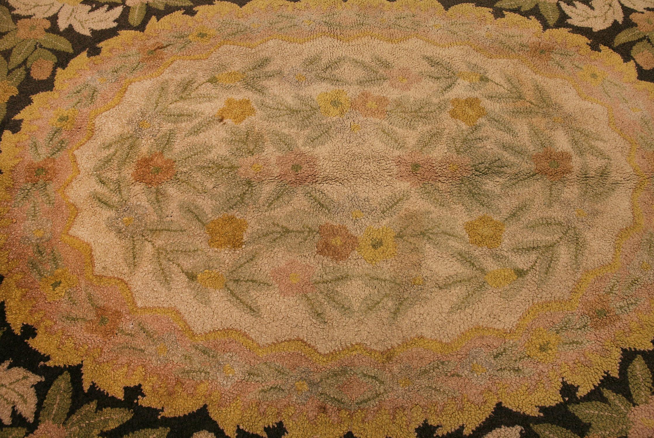 This is an American hook rug woven in the United States during the 1920’s and it measures 265 x 170 in cm. This rug has an oval shape as many American hooked rugs do. It has been designed with a floral border and floral field. This rug is in