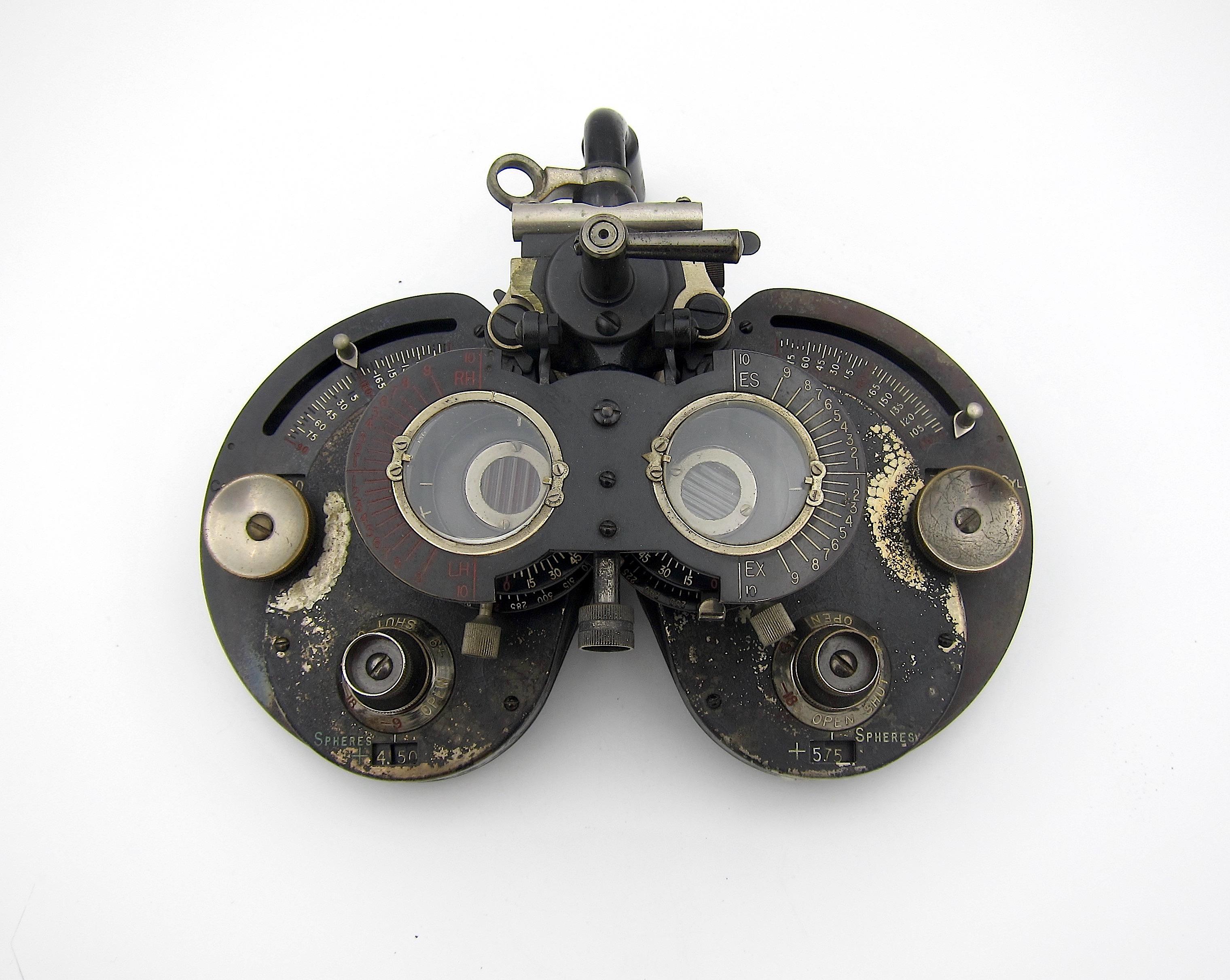 An early 20th century American vision testing device called a phoropter, an ophthalmic instrument patented in 1917 as a Genothalmic Refractor. A phoropter is a binocular refracting instrument containing a variety of convex and concave lenses used by