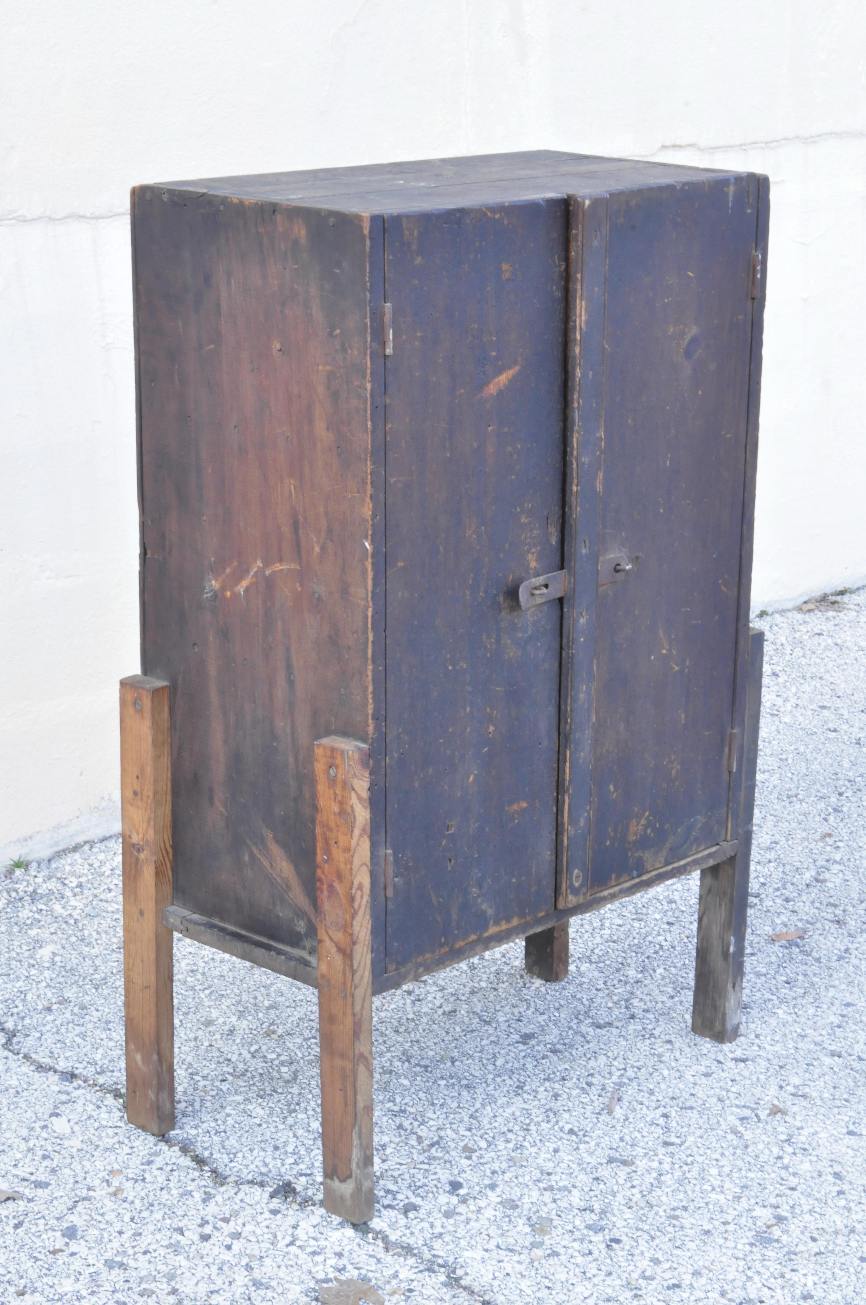 Antique American primitive distressed solid wood 2-door storage tool cabinet cupboard pantry. Item features wonderful patina, solid wood construction, distressed finish, 2 swing doors. Legs appear to be a later addition, circa early to mid-1900s.
