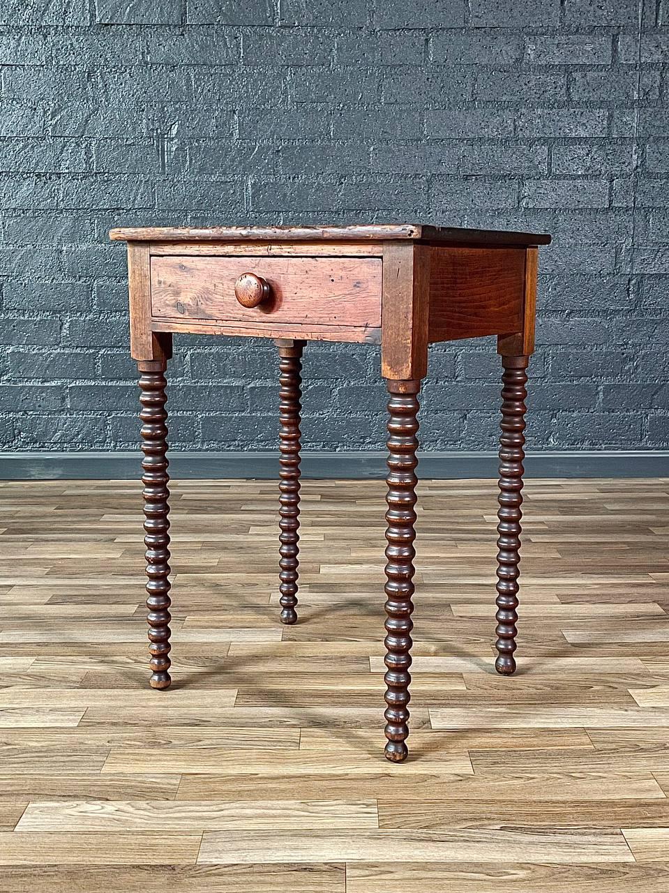 Condition: Original Vintage Condition

Crafted in the early 1900s, this Antique American Primitive Spool-Turned Side Table embodies the warmth and character of early handcrafted furniture. Made from patinated pine, its rich, timeworn surface tells a