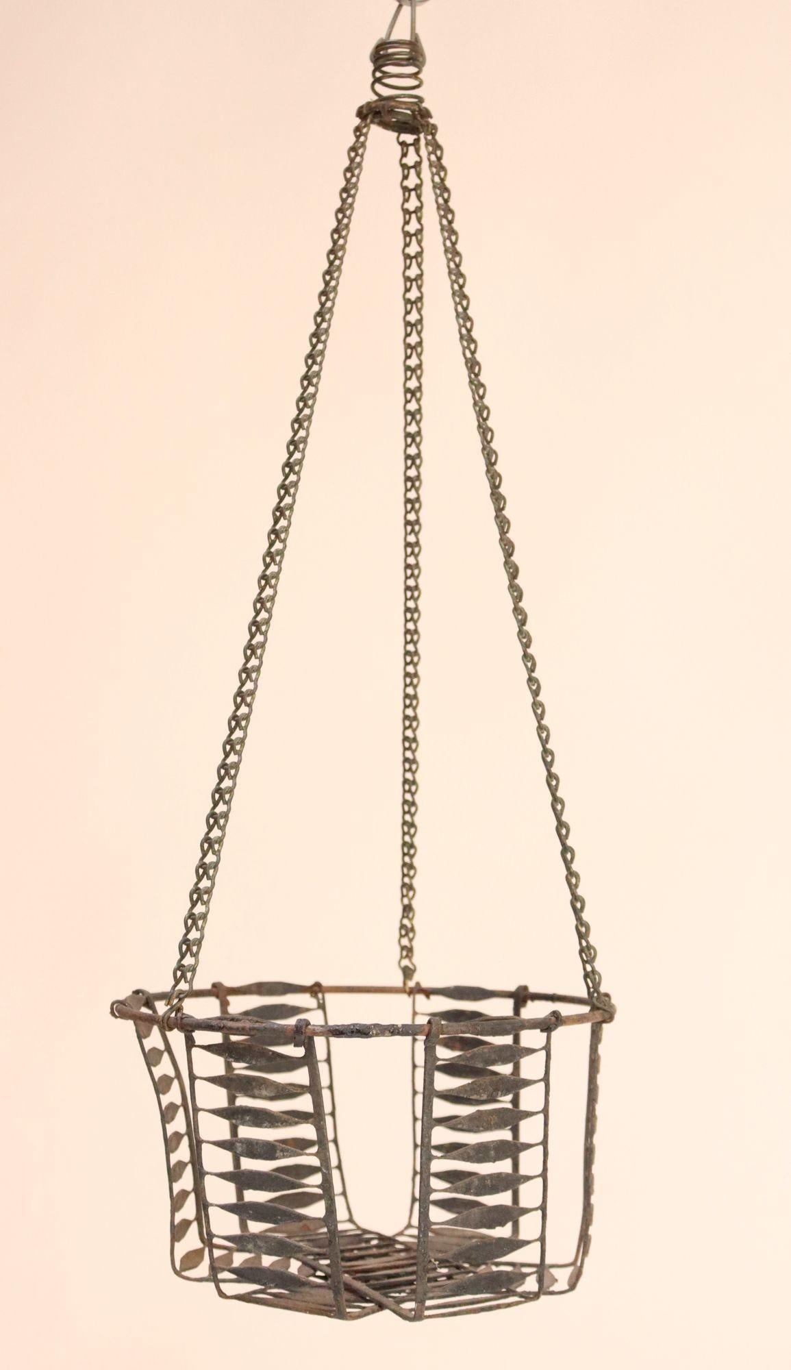 Rustic metal wire egg basket with original hook and chain (ca. 19th Century, USA).
Though originally used for housing eggs, this hanging basket doubles as a catchall or planter and is suitable for indoor and outdoor use.
Good, vintage condition with