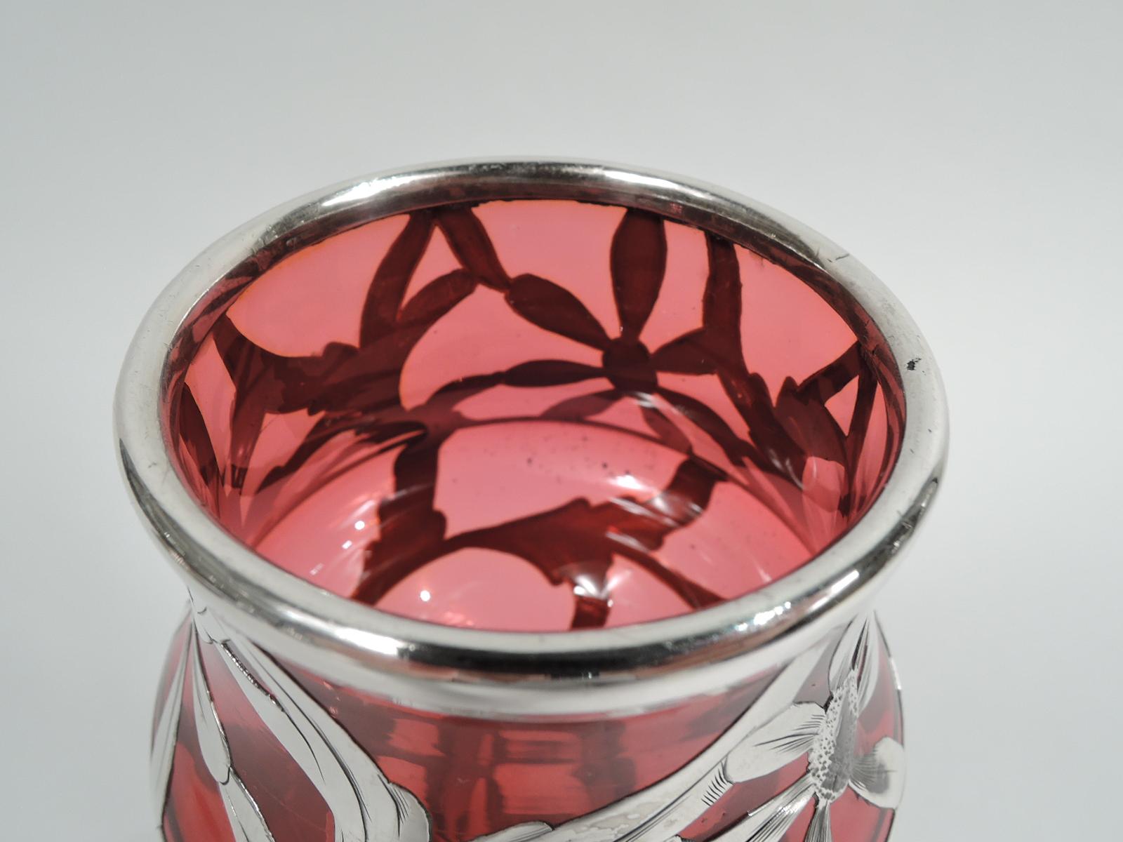 Turn-of-the-century American glass vase with engraved silver overlay. Tulip-form with flower-bud bowl on baluster stem on gently raised round foot. Overlay in form of daisy flower heads and tendrils. Glass is red except foot, which is clear. Marked