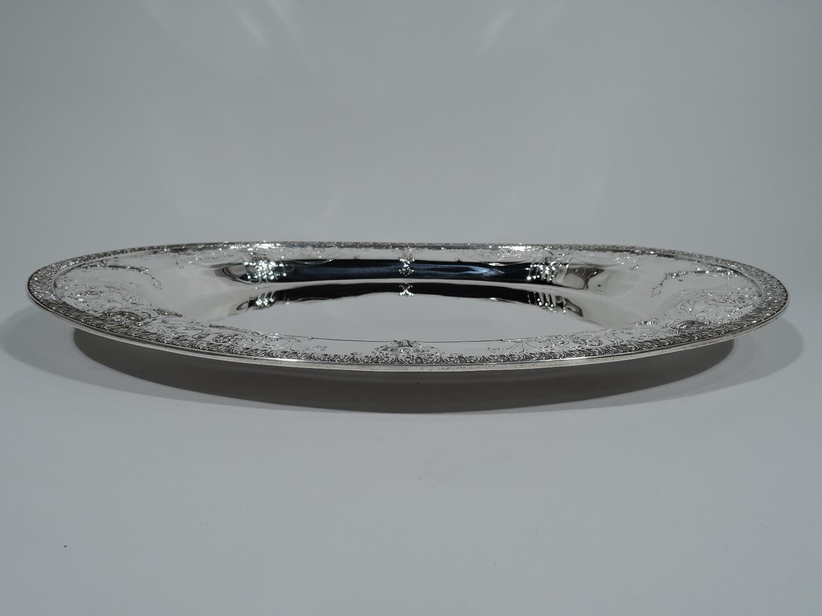 Regency Revival sterling silver serving tray. Made by Black, Starr & Frost in New York, circa 1910. Oval well and wide shoulder with loosely chased covered vases, paterae, foliage, and flowers. Leaf-and-dart rim. Fully marked including no. 1452/8.