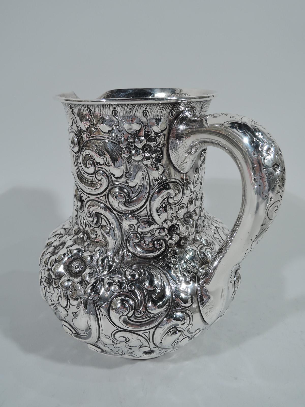 Victorian sterling silver water pitcher. Made by Theodore B. Starr in New York, circa 1880. Globular with drum-form neck, small lip spout, and scroll handle. Allover repousse flowers, foliage, and scrolls. Pretty and tactile. Interlaced script