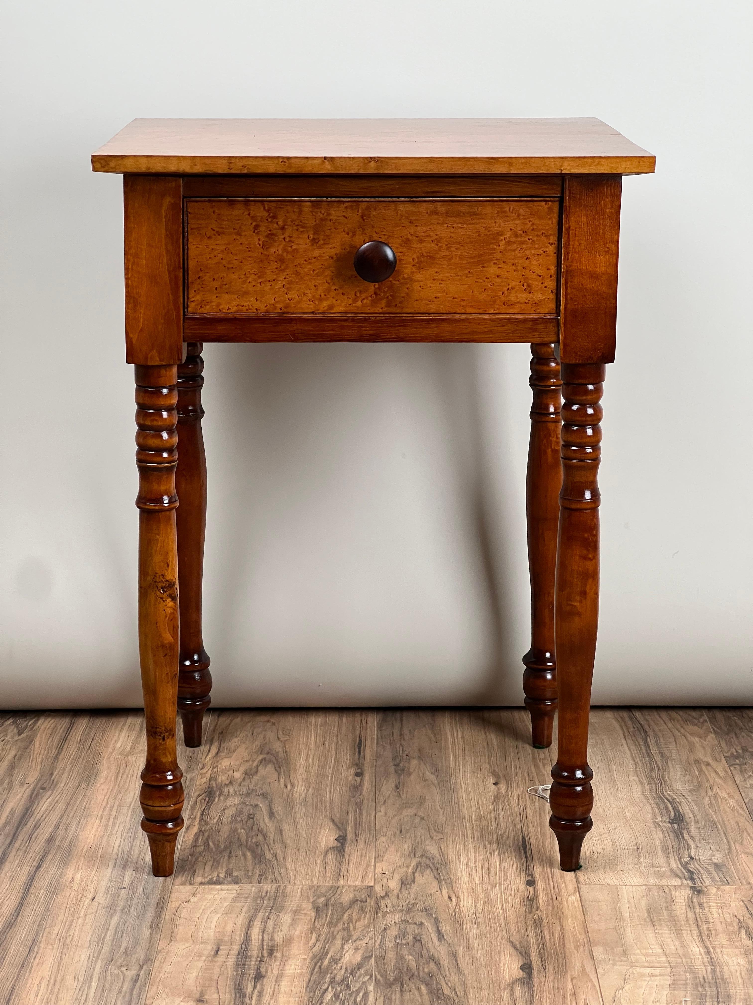 Este antiguo mueble americano Sheraton de un cajón, de mediados del siglo XIX, está fabricado en hermoso arce ojo de perdiz con cálida pátina y grano fino. La forma es característica del estilo Sheraton, con sus proporciones equilibradas, sus patas