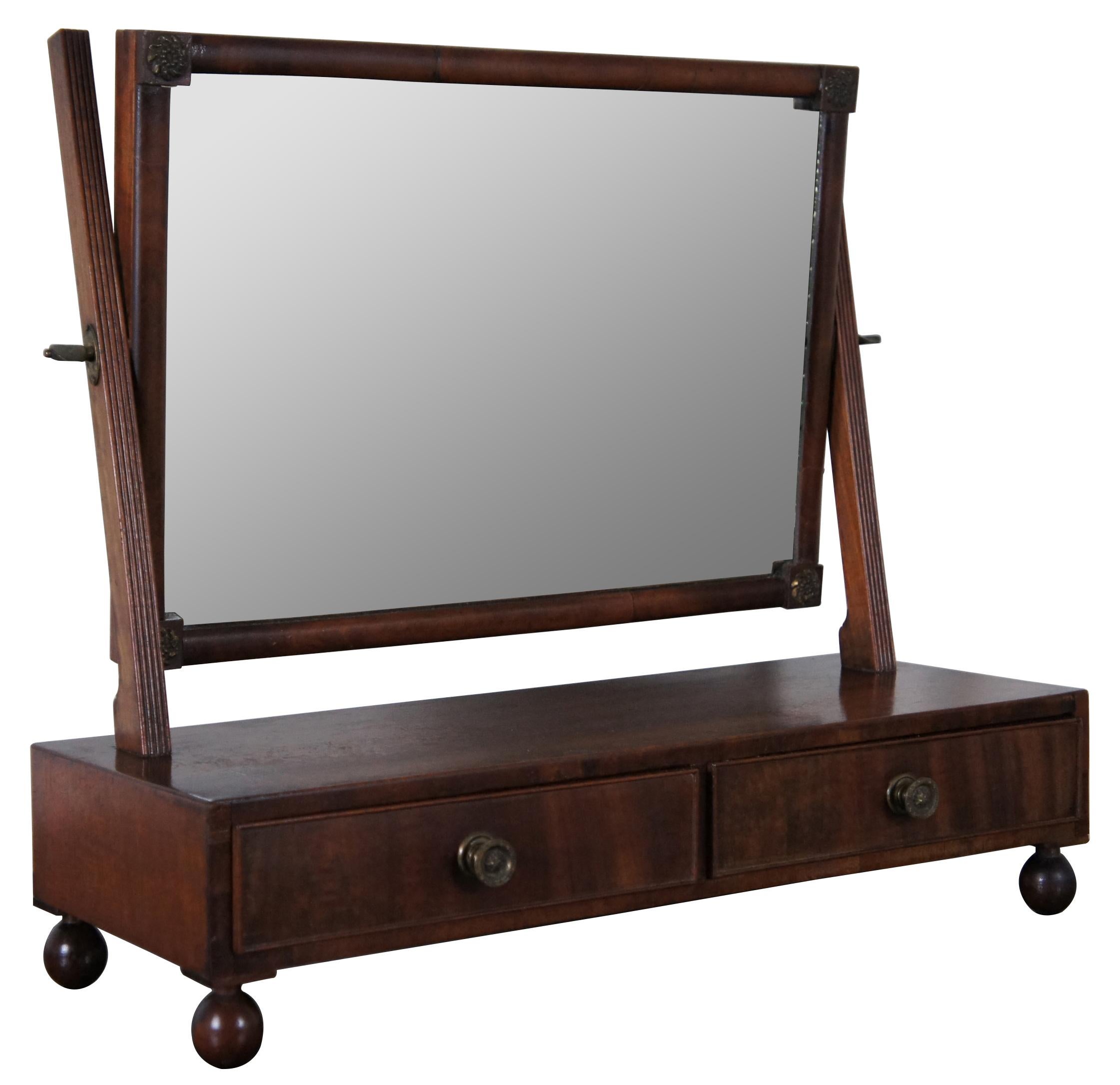 An exquisite Sheraton Period shaving stand. A rectangular form made from mahogany with two drawers over ball feet and swivel top mirror. Includes hand dovetailing, ornate brass hardware and flame mahogany front. 

Measures: 20.5” x 7.75” x 18.25”