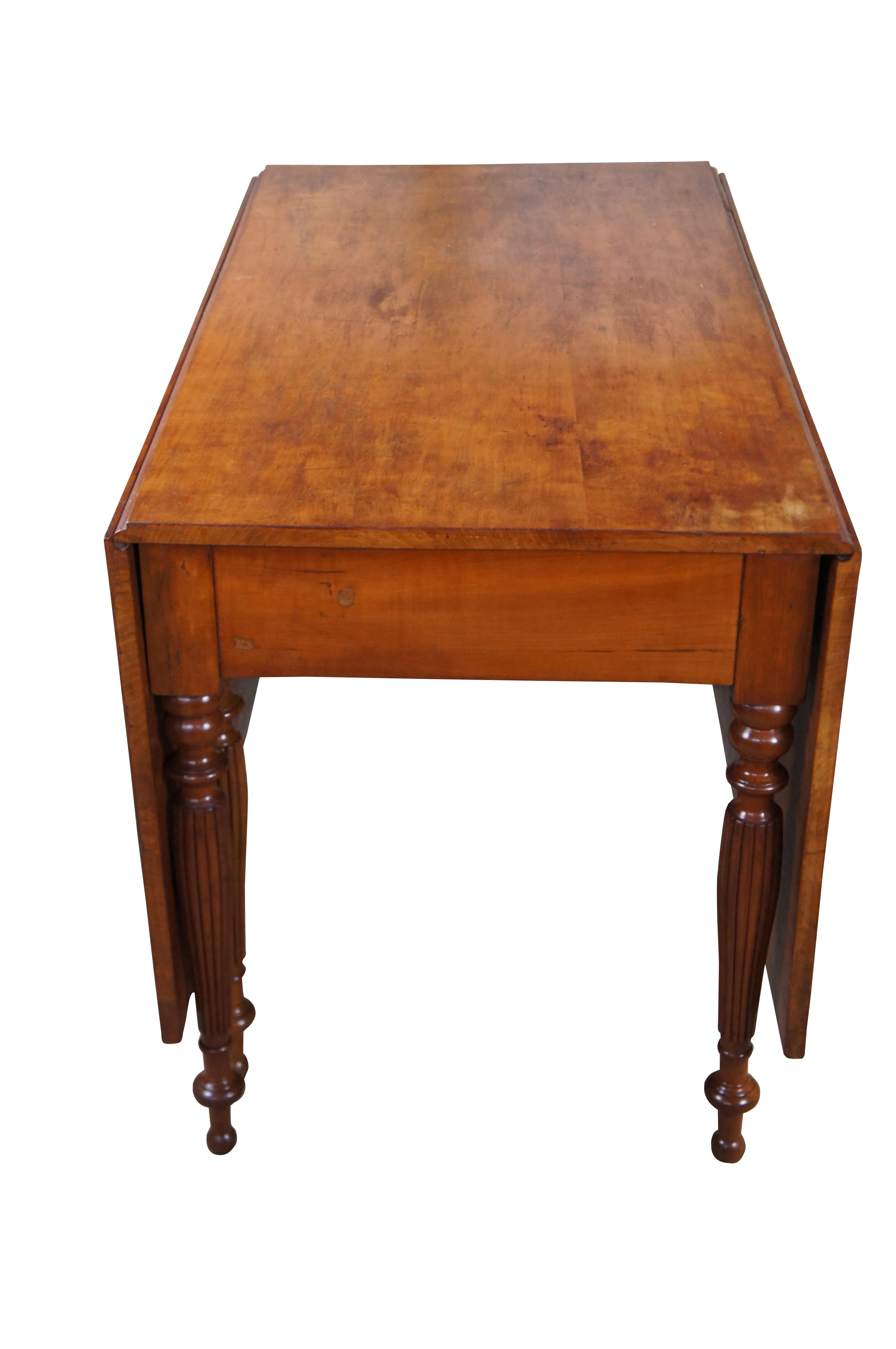 Exquise table de salle à manger Sheraton américaine du début du 19e siècle.  Elle présente une forme rectangulaire avec de longues feuilles tombantes en cerisier massif.  La table est soutenue par des pieds tournés et cannelés menant à des pieds en