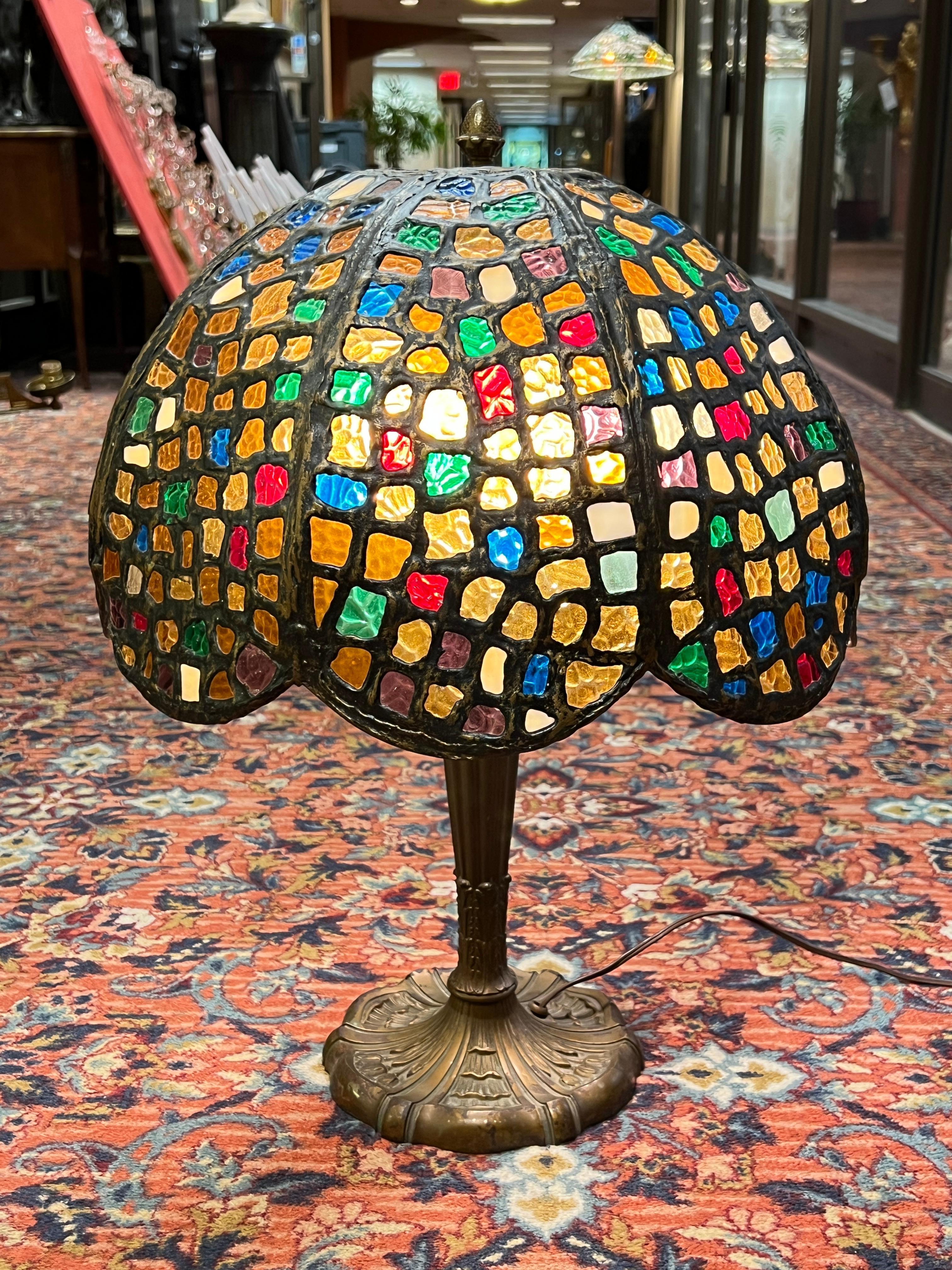 Beautiful antique American Arts and Crafts period table lamp in bronze with stained glass shade by the Miller Lamp Company.  With two modern standard size sockets and cord, ready for use.