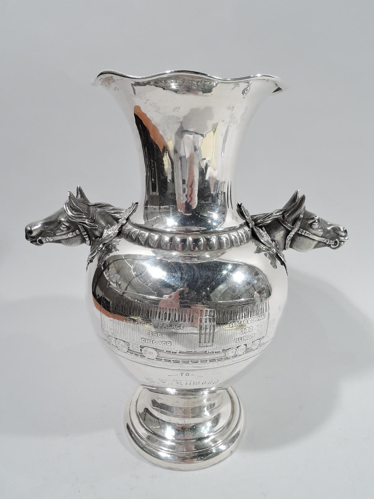 Turn-of-the-century sterling silver trophy cup. Made by Peter L. Krider in Philadelphia. Baluster body on raised foot. Straight neck with ruffled rim. Gadrooned border. Mounted to shoulder are two cast horse heads wreathed in laurel. Acid-etched and