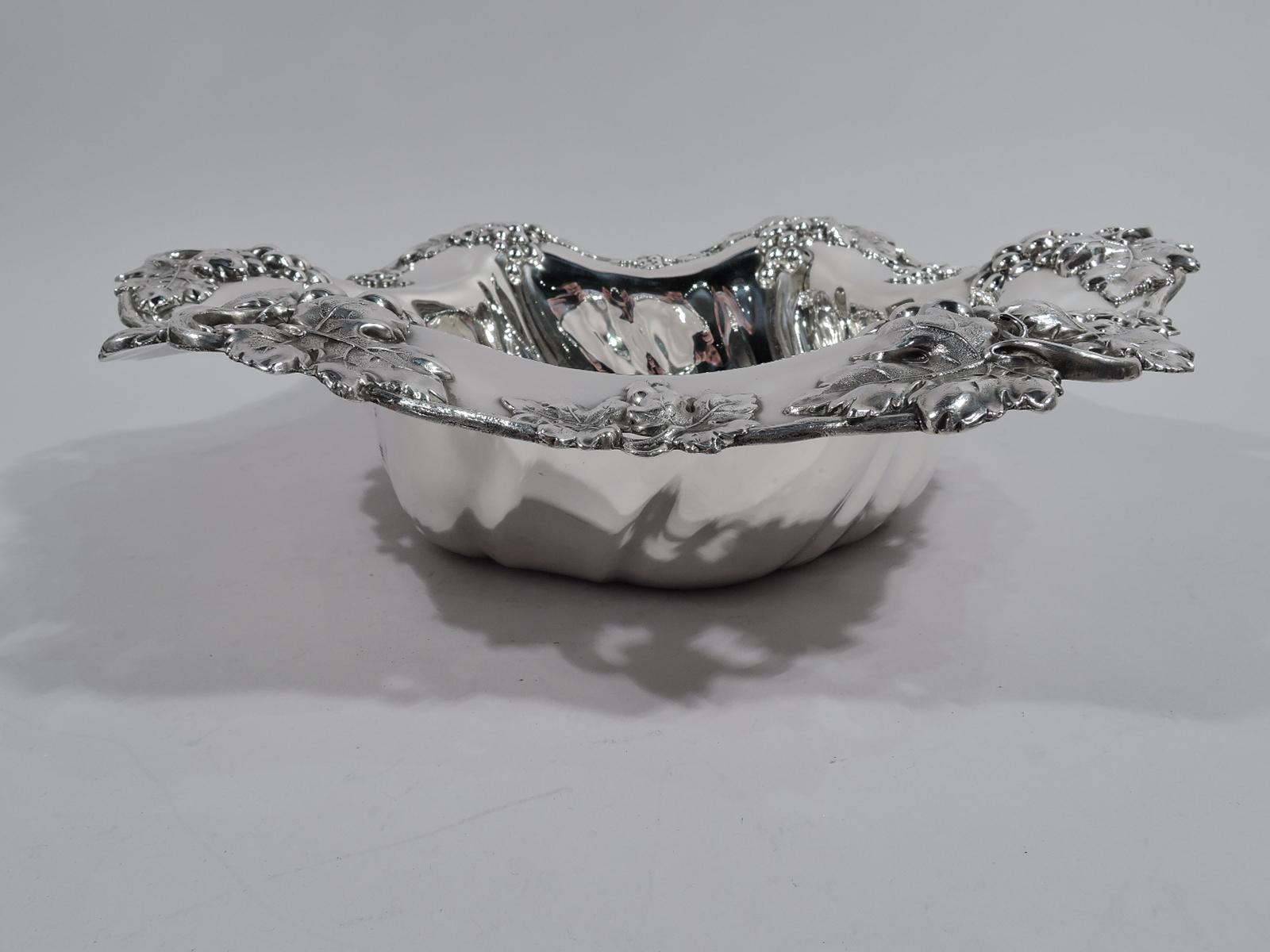 Beautiful sterling silver centerpiece. Made by Mauser in New York, circa 1890. Round well with twisted flutes. Wide and wavy rim with applied and stippled fruiting grapevine; some bunches pendant from open rings. Substantial and tactile as well as