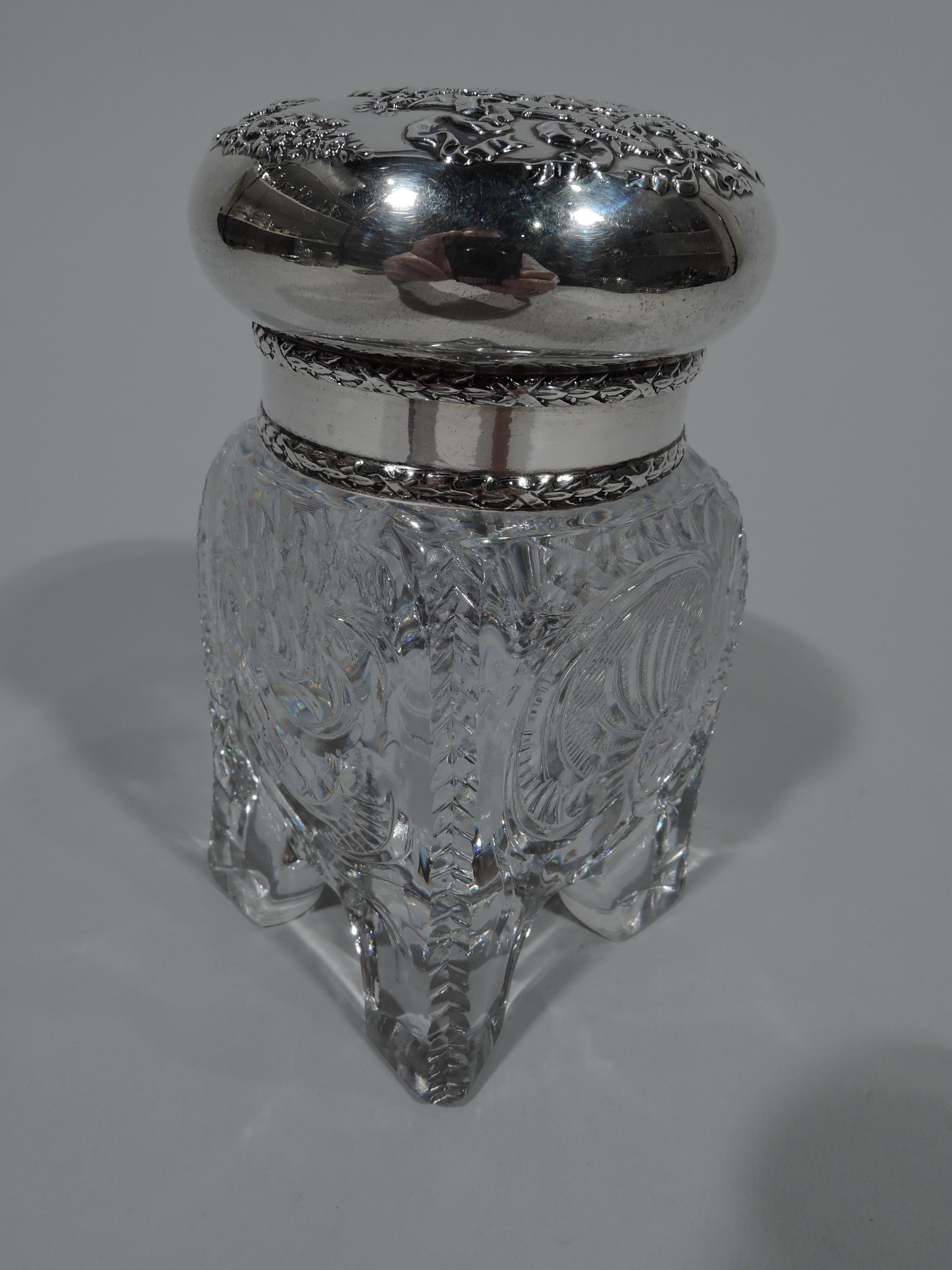 American sterling silver inkwell, circa 1880. Four gently curved sides on corner block supports. Cut ornament including scrolls, flowers, and chevrons. Sterling silver neck collar with imbricated leaf borders. Hinged bun cover same; top has chased