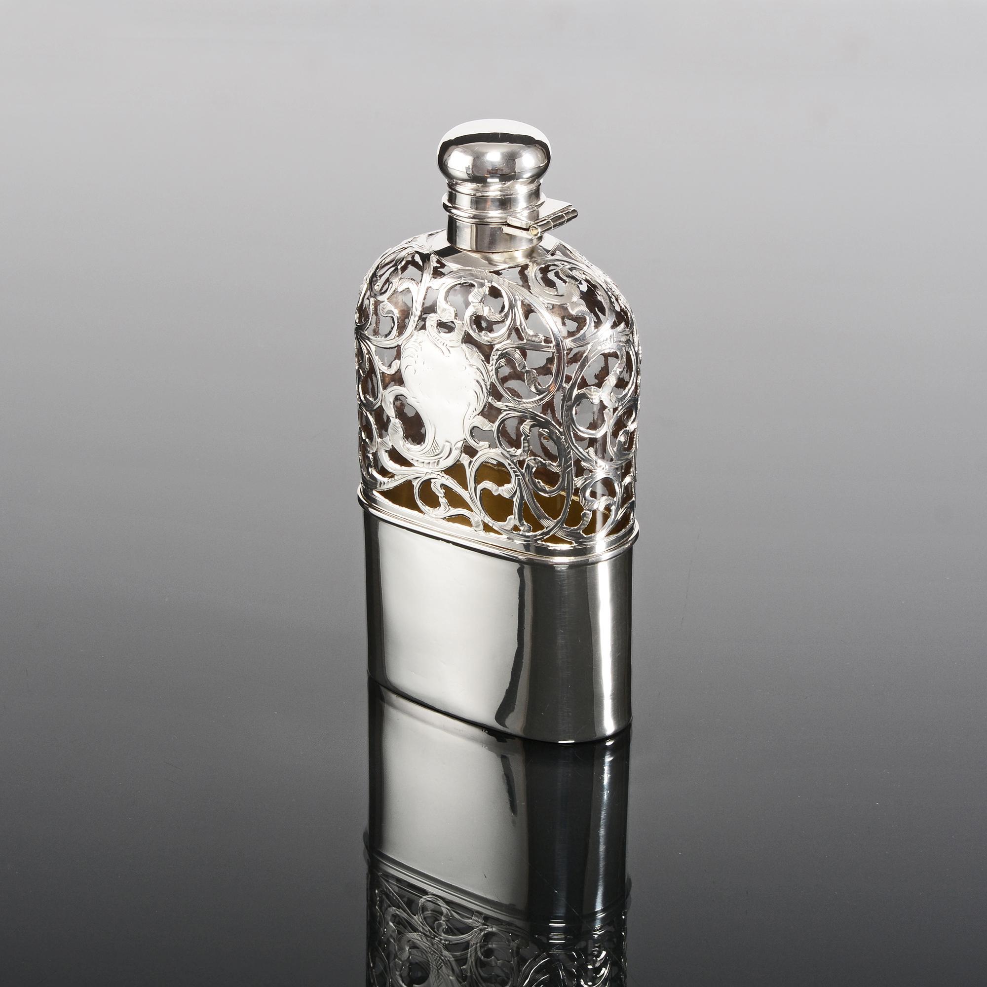 Antique American hip flask with glass body, silver collar and fitted with a domed, one-twist, bayonet cover. The glass body features hand engraved silver openwork overlay in a scrolled leaf pattern that is enhanced with hand engraving.  The