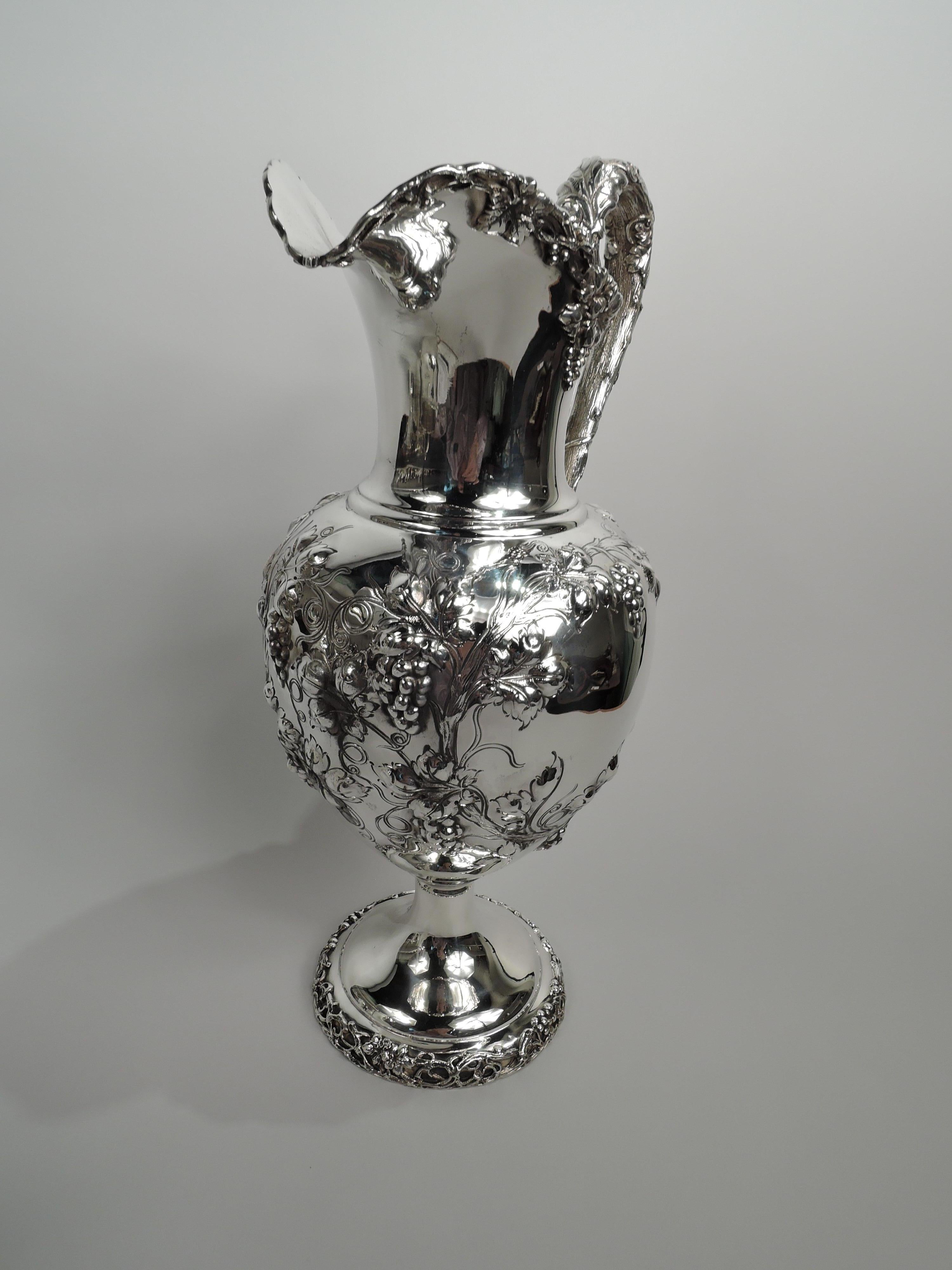 Pichet victorien en argent massif. Fabriqué par Dominick & Haff à New York en 1894. Corps ovoïde avec des vignes fructifères ciselées formant 2 cadres irréguliers (vacants). Bouche en forme de casque et pied surélevé et rond avec le même appliqué