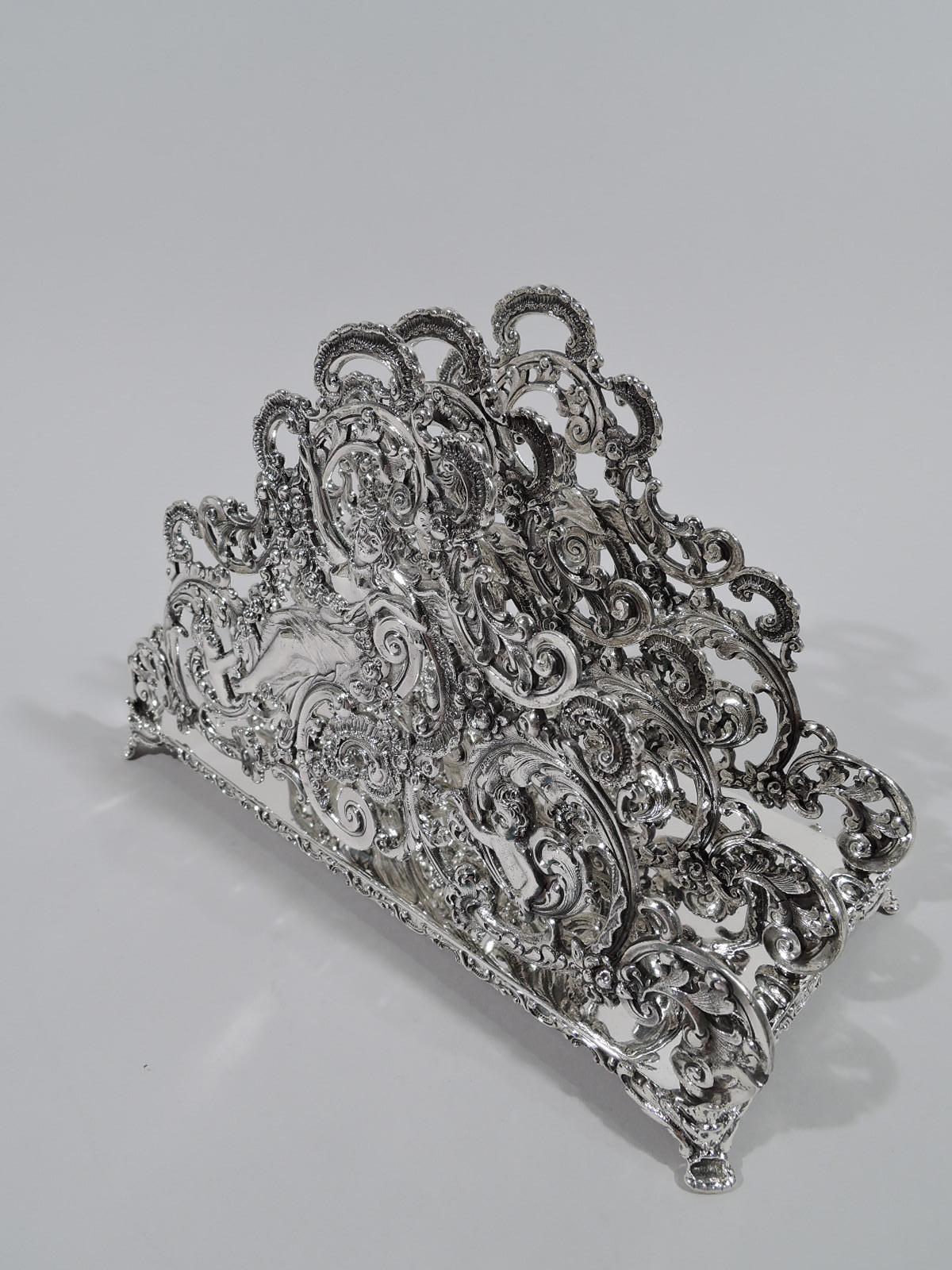 Turn-of-the-century Art Nouveau Rococo sterling silver letter rack. Plain rectangular base with scrolled rim and foliate corner supports. Three identical partitions: buxom lolling lady and two cherubs holding garland at ends, surrounded by open