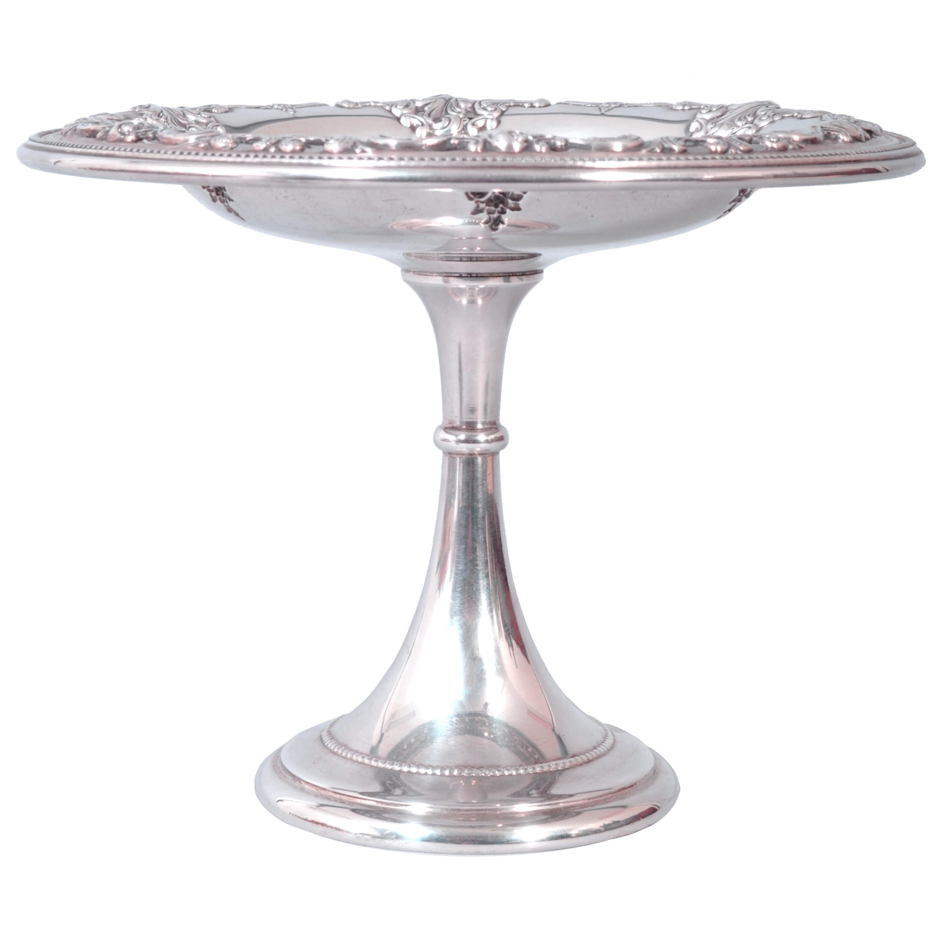 A good antique American sterling silver tazza or compote by R. Wallace & Son Silversmiths, circa 1925.
The circular tazza with a shallow bowl with scrolled baroque repousse decoration and bordered with a band of beaded design, the tazza is raised on