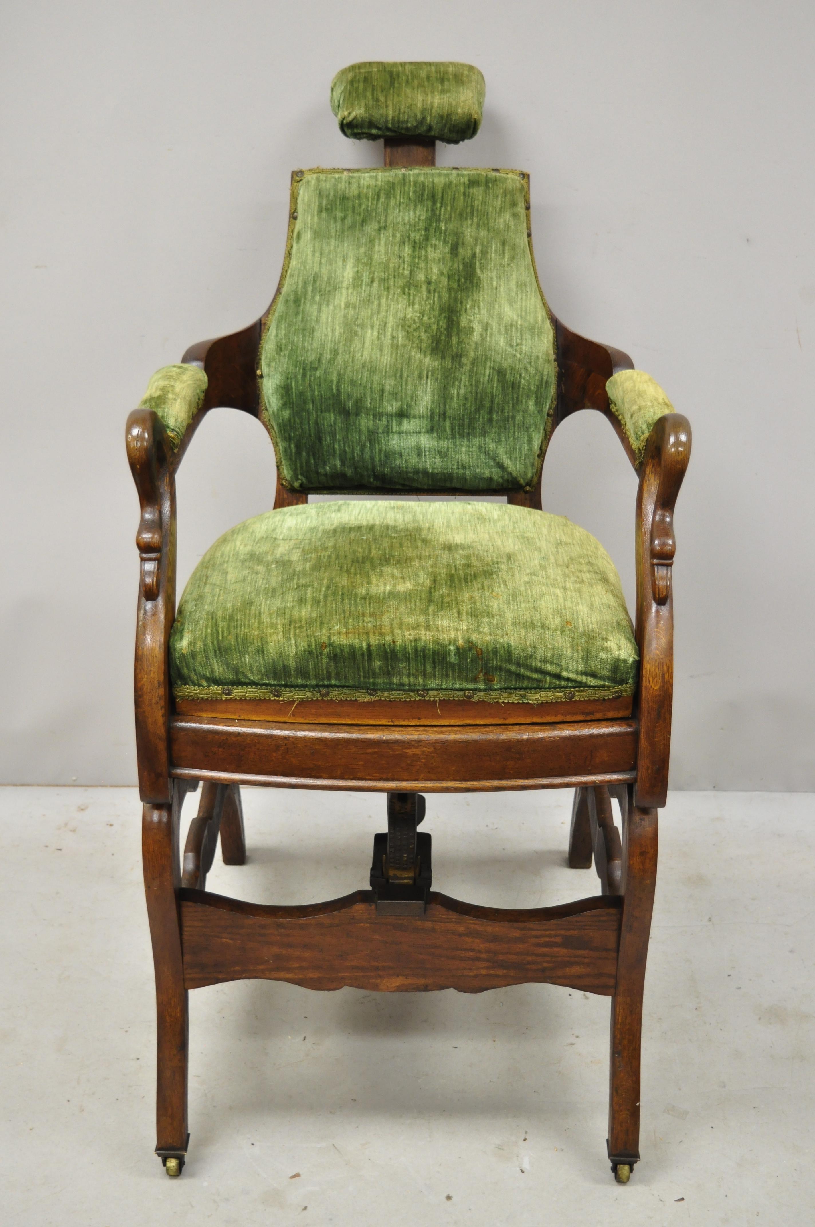 Antique American Victorian adjustable archer barber chair and footrest ottoman. Item features an adjustable chair, footstool with cast iron footrest and signatures, swan carved arms, original green velvet upholstery, adjustable headrest, solid wood