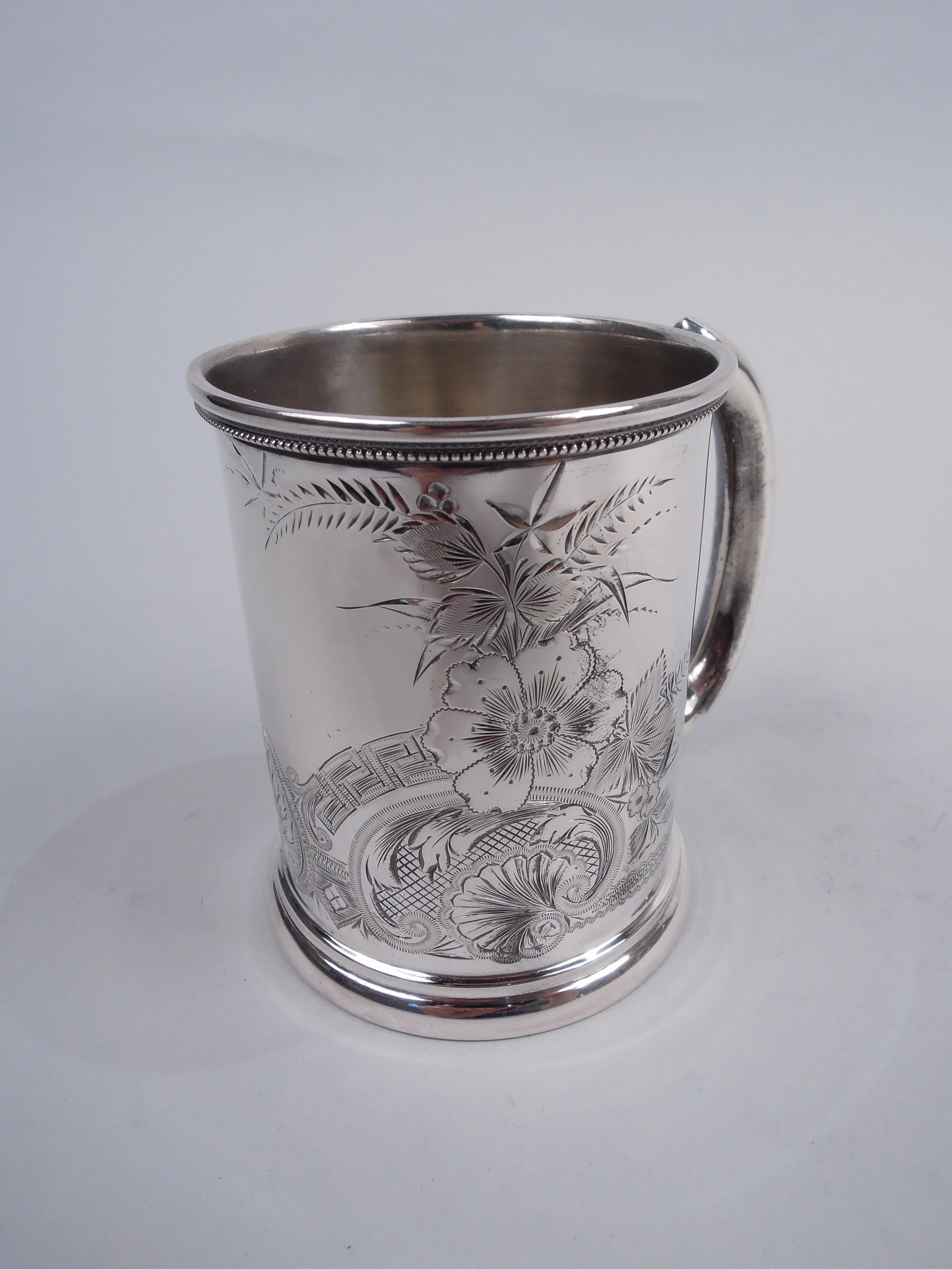 American Aesthetic Classical sterling silver baby cup, ca 1870. Straight sides with c-scroll handle and stepped spread foot. Engraved flowers and leafing scrolls amidst palmette, scallop shell, Greek Key, and diaper. Beaded, pointille, and wavy