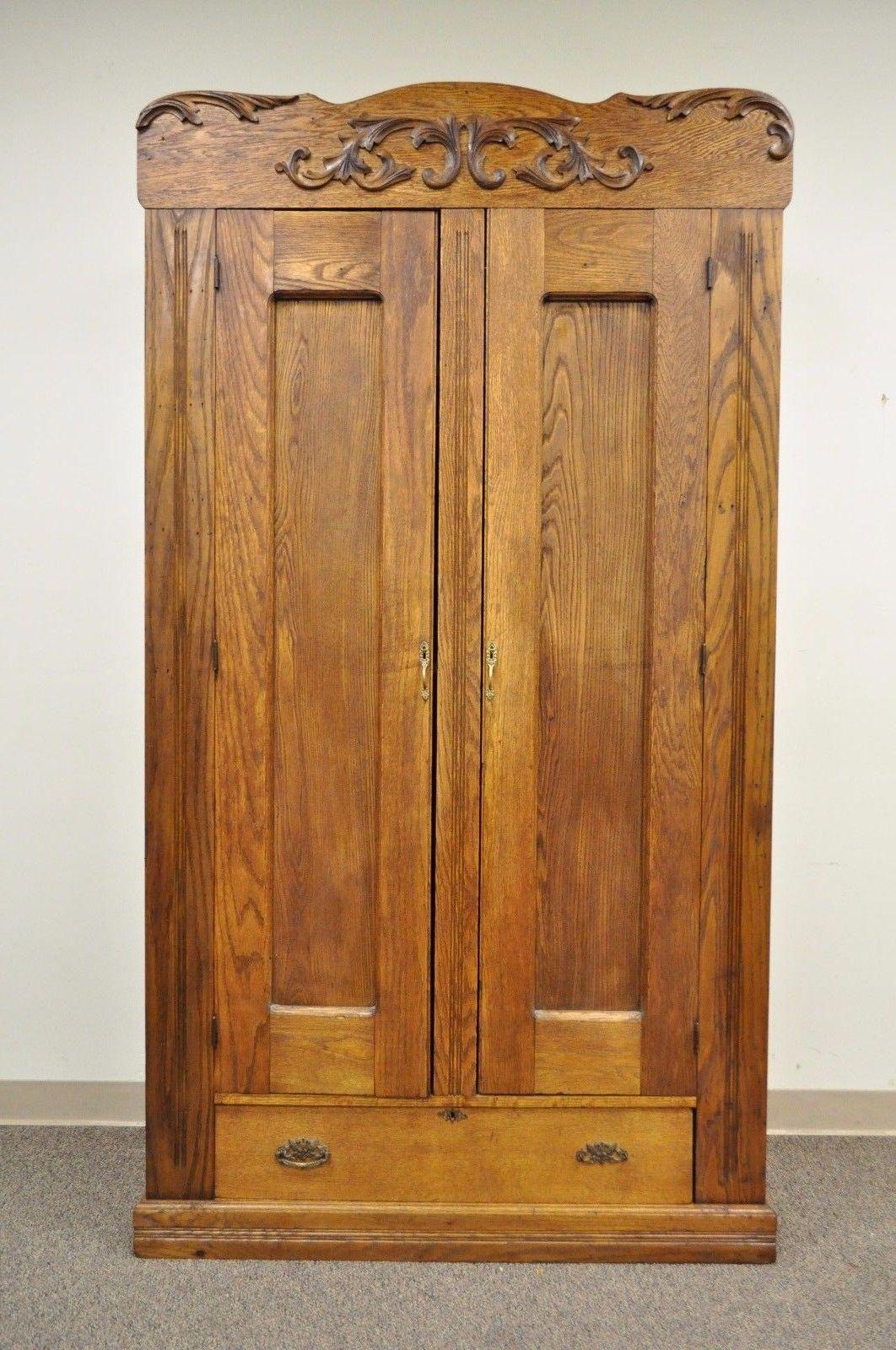 Tall Antique American victorian golden oakwood wardrobe. Item features solid oakwood construction, applied carved wood accents, single Drawer, two swing doors, interior shelf, brass hardware, paneled back, tall stately form, true antique wardrobe,