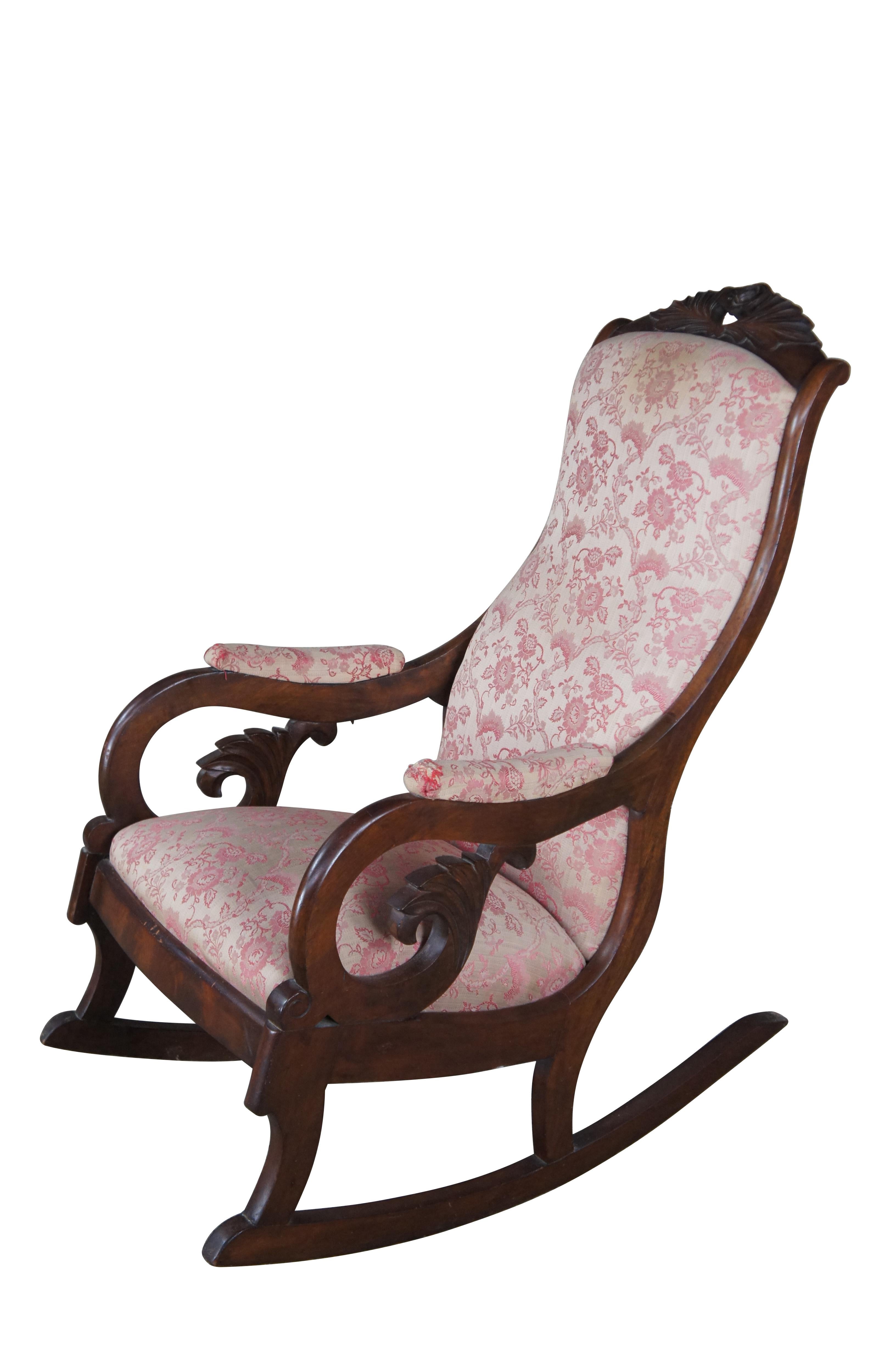 An exceptional American Late Classical Regency and Empire inspired rocking chair, circa 1850s.  Attributed to Thomas Day.  Made from mahogany with a high rose carved contoured back leading to downswept padded and scrolled arms.  The chair features a