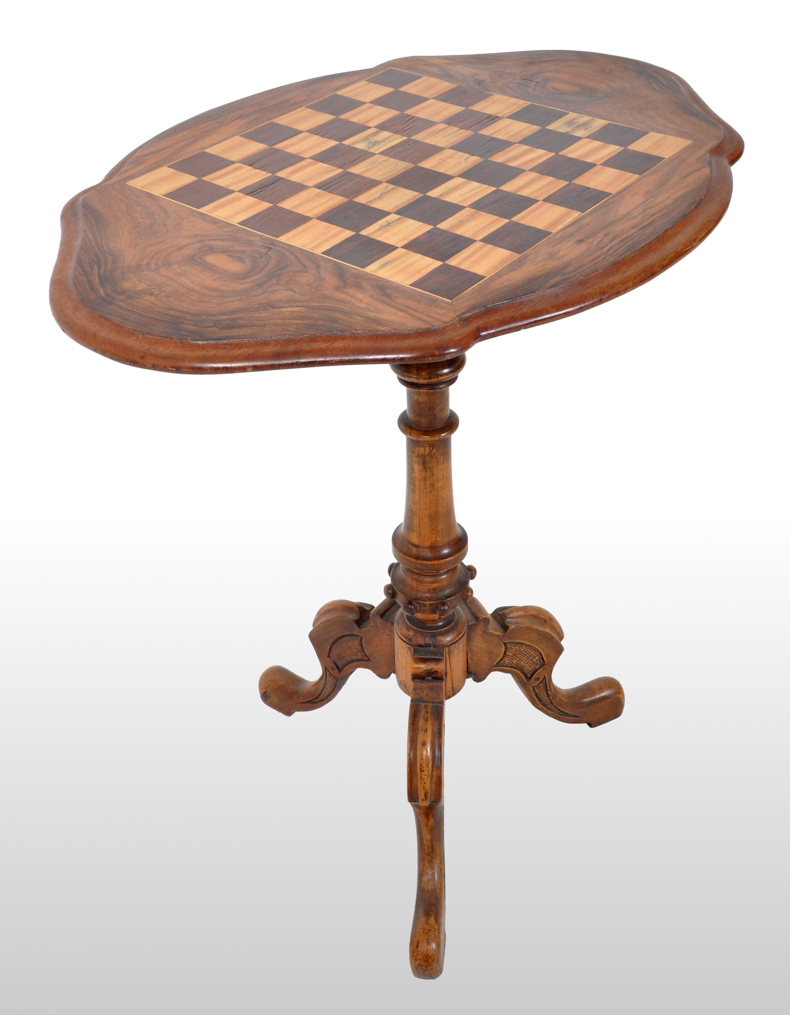 Antique American Victorian walnut tripod games / chess table, circa 1870. The table having a shaped top and inlaid with a chess/checker board, raised on a turned pedestal column and terminating to a carved tripod base.