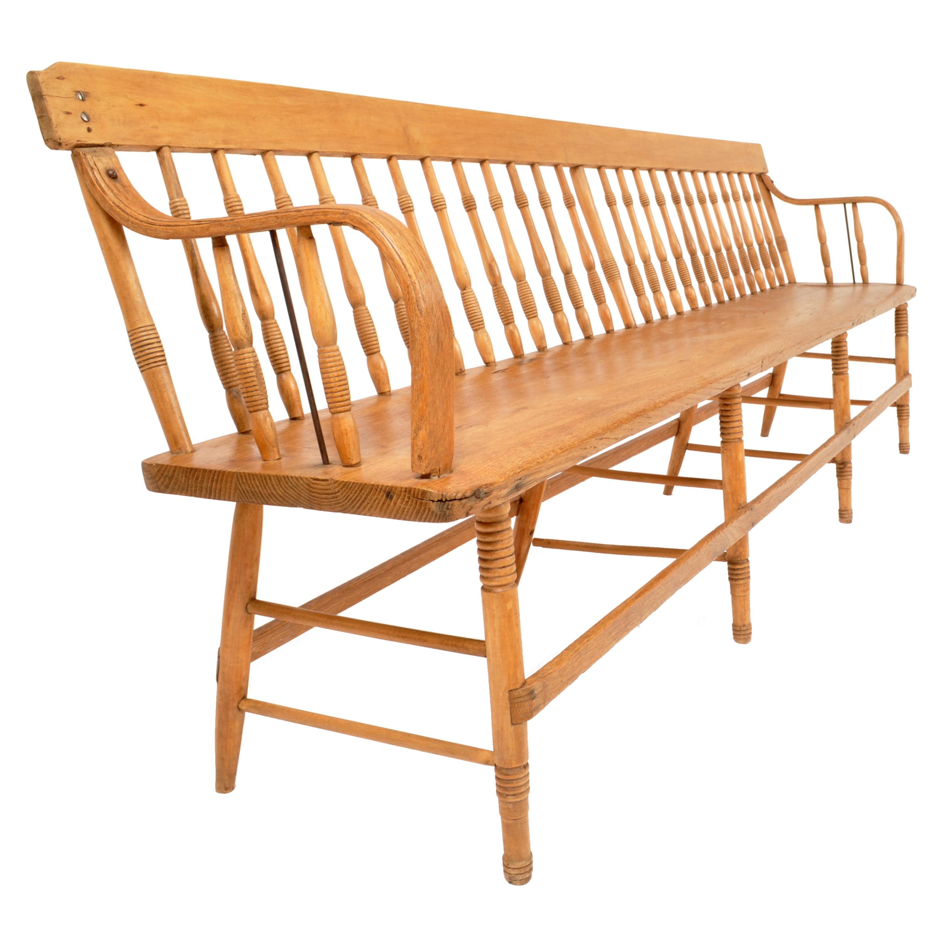 A very good, long (8ft) antique American pine and maple Colonial style spindled back deacon's bench, most likely New England, circa 1840. The bench having a single back splat with turned spindles below and having 'bentwood' arm supports at each end.