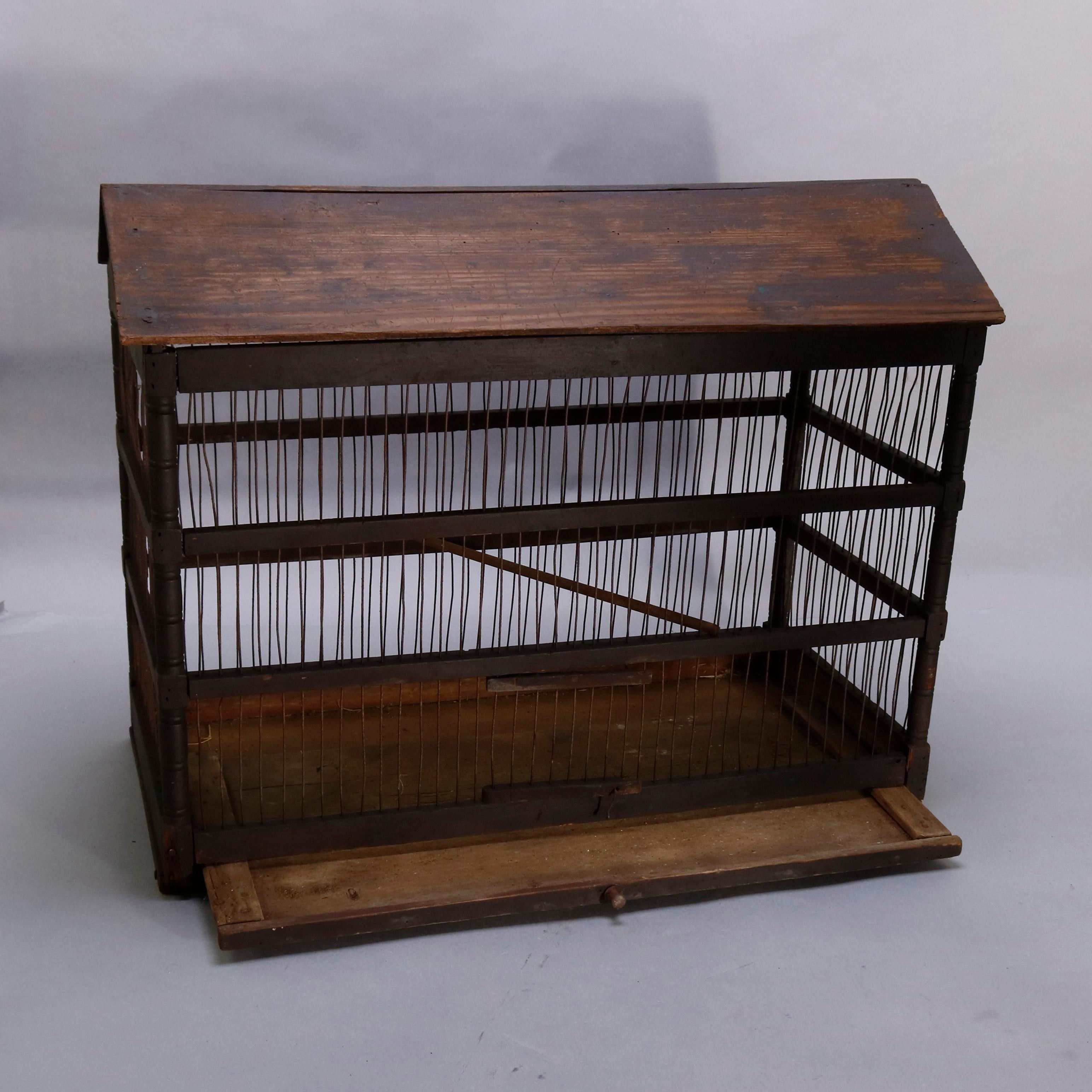 An antique Americana Folk Art bird cage offers wood construction in house form with door and pullout / pull-out tray and having wire caging, circa 1860

Measures: 22.25
