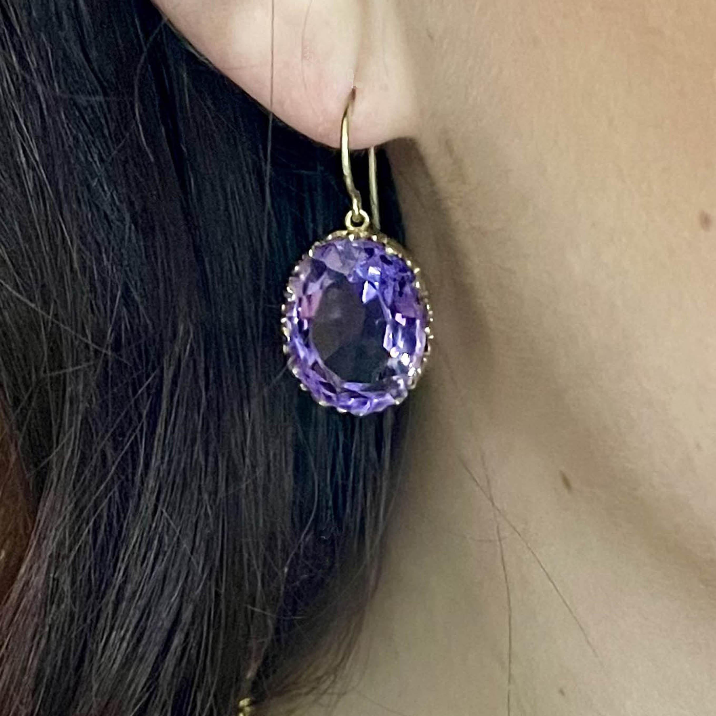A pair of antique, amethyst and gold, drop earrings, with large, oval faceted amethysts, in open backed decorative, trefoil design, gallery strip bezel settings, on gold wires, circa 1880. Estimated total weight of amethysts 33.88 carats.

Some of